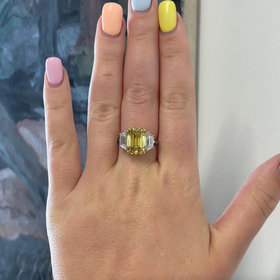 Vivid Fancy Yellow Diamond Engagement Ring. The main diamond is GIA certified (#1162484187) 7.01 carat, vivid fancy yellow emerald cut. Accented by two GIA certified trapezoid diamonds. Circa 2021. The ring is new size 6 3/4 and can be resized.