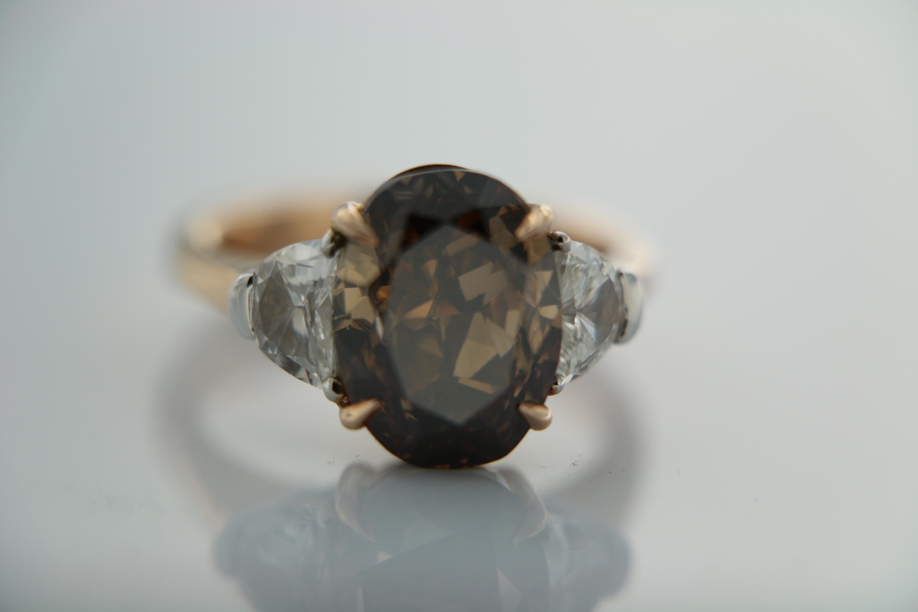 A magnificent ring designed and created by Moguldiam Inc in 18k rose gold features a GIA certified natural fancy dark orange brown oval brilliant weighing 7.07 carat with SI 2 clarity in the center flanked by  half moon diamonds on each side