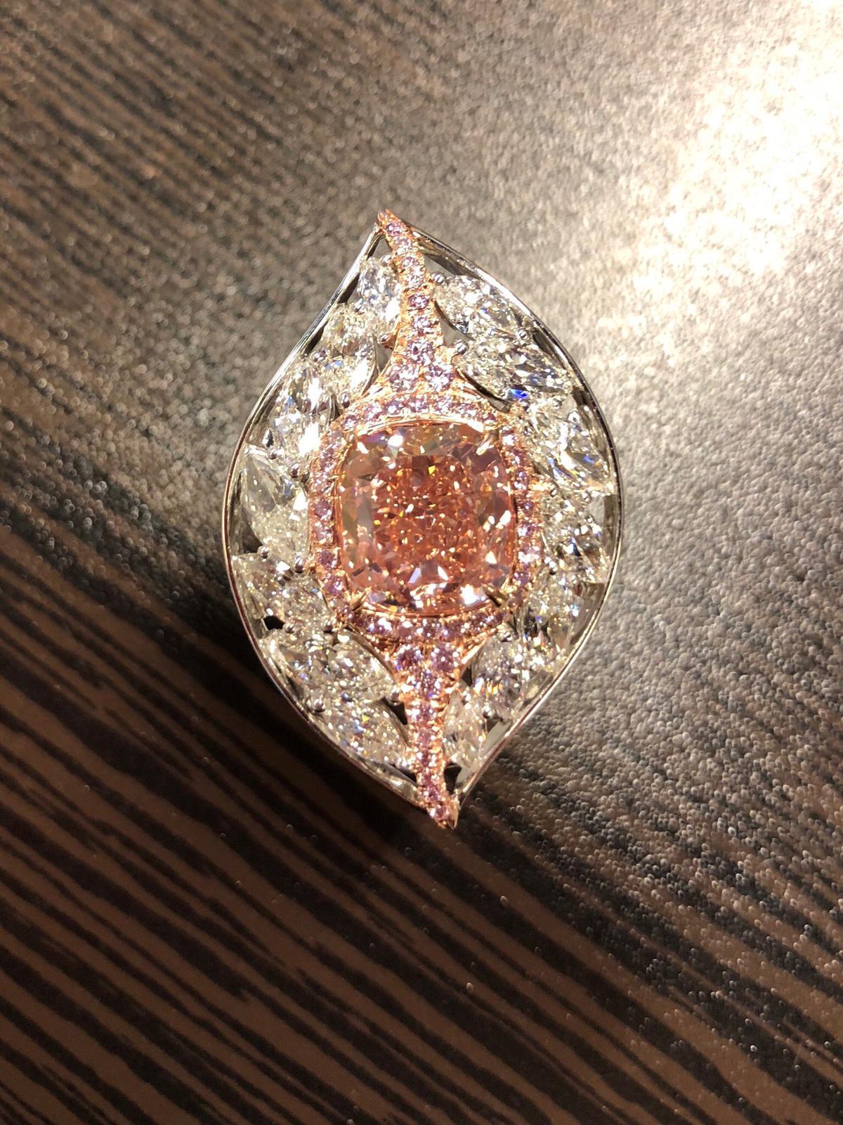 Cette bague magnifique et unique présente un diamant brillant coussin certifié par le GIA, de couleur rose orangé brunâtre et sans défaut interne, pesant 4.10 carats, entouré de méles roses pesant 0.37 carats et de diamants marquises blancs pesant