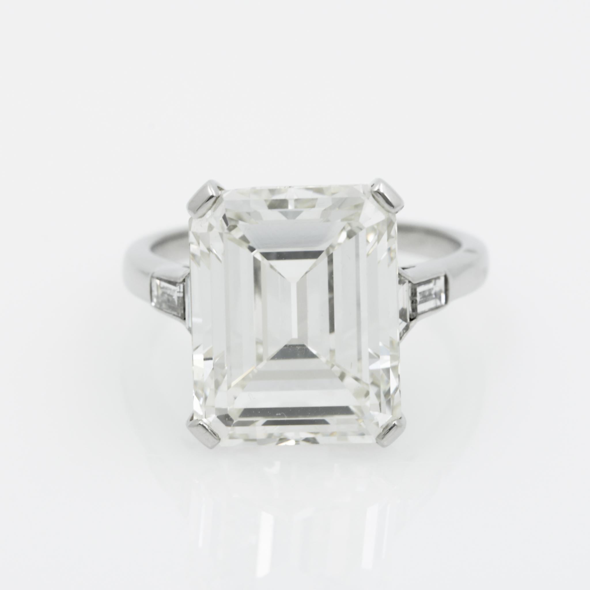 This platinum five stone ring features a 9.66 carat Emerald cut diamond that has K color and S1 clarity, and is GIA certified. It also showcases two trapezoid and two tapered baguette diamonds with a combined total weight of 0.32 carats with I-J
