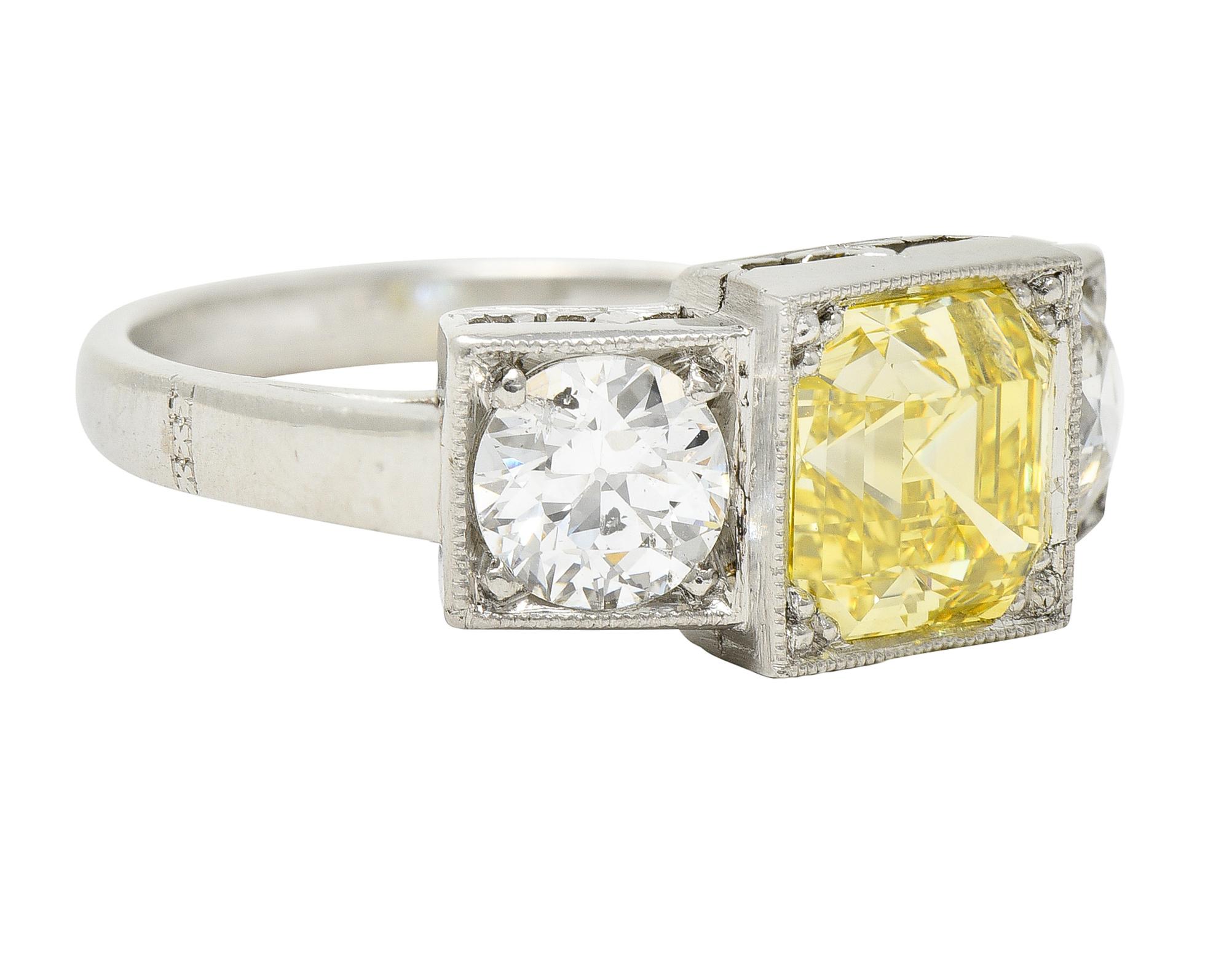 Centering an asscher cut diamond weighing 2.04 carats - Natural Fancy Intense Yellow in color with VS1 clarity. Set with tri-beads in a square from head and flanked by two old European cut diamonds. Weighing approximately 1.16 carats total - H and I