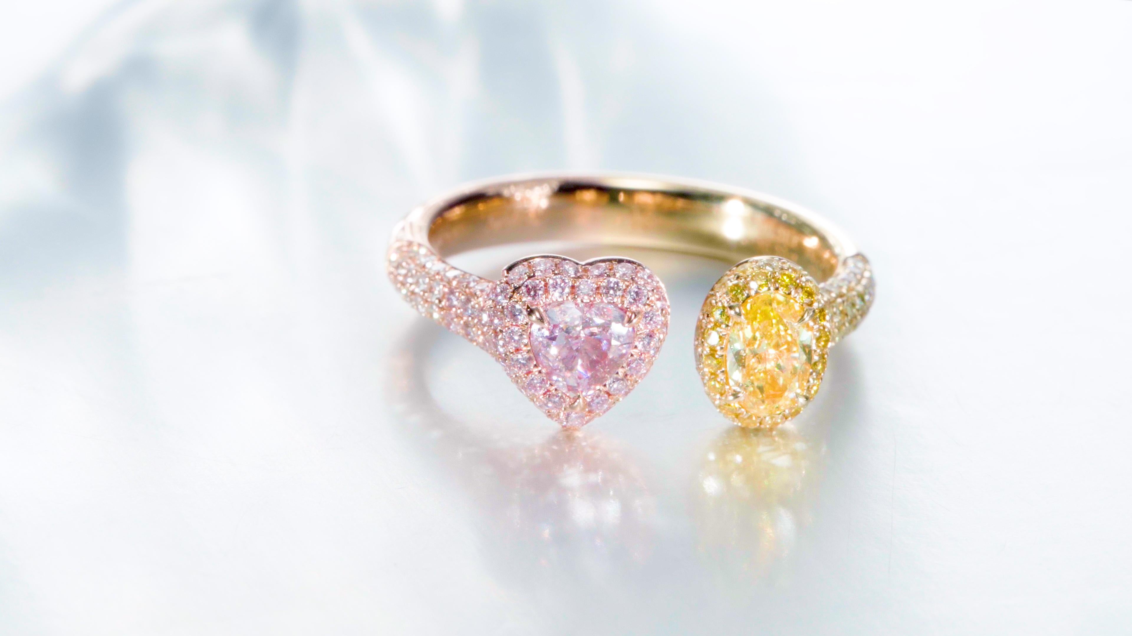 Introducing a breathtaking 18k Yellow Gold Heart-Shaped Diamond Ring, featuring two exquisite center stones that capture the essence of luxury and elegance. The first center stone is a Fancy Light Purplish Pink diamond (GIA NO. 1459468637), weighing