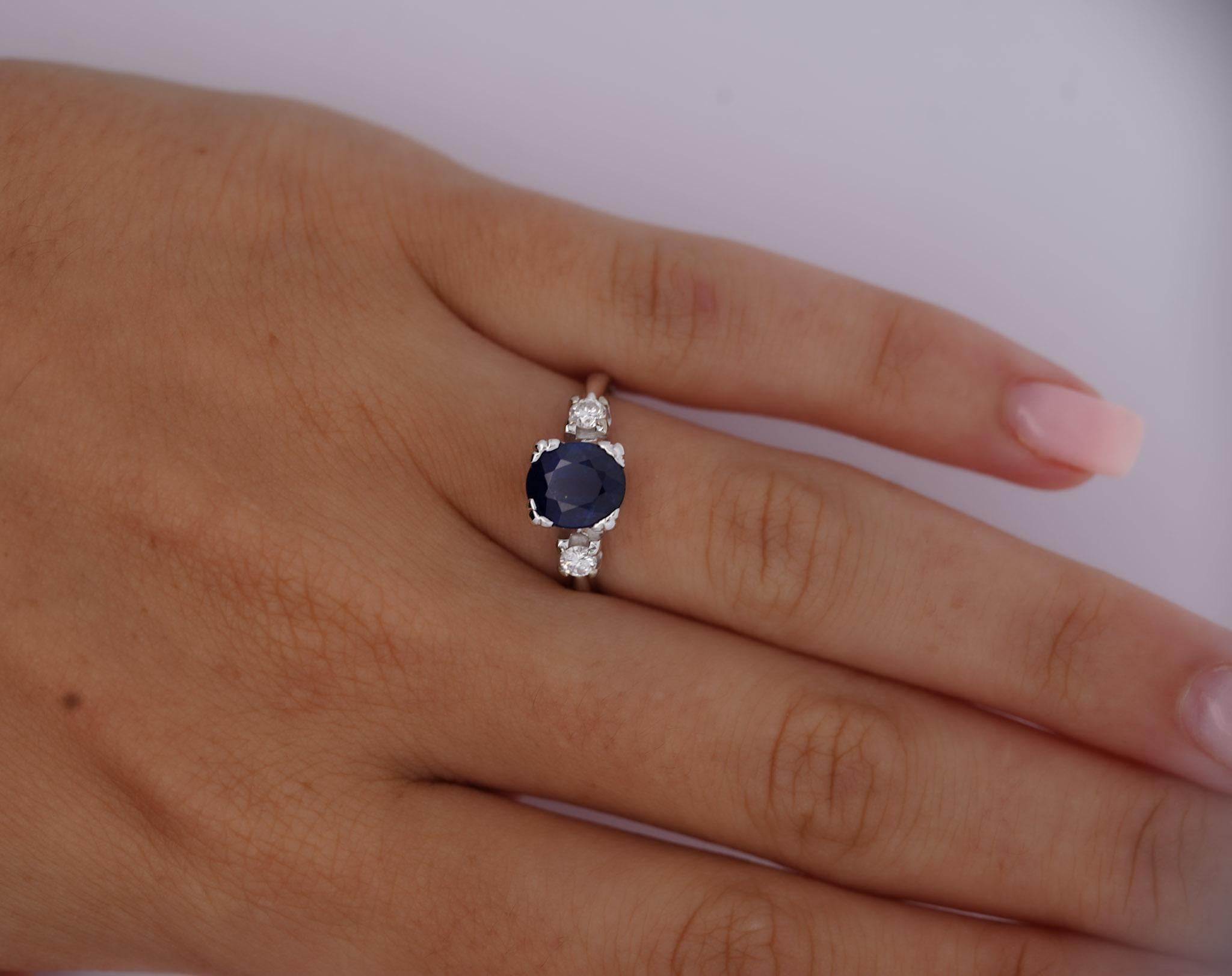 Presented here is a GIA certified 1.85-carat oval-cut sapphire and round diamond 3-stone ring. On its shoulders rest two round-cut, brilliant diamonds, totaling 0.22 carats, secured in a classic 4-prong setting. The sapphire's mesmerizing, deep