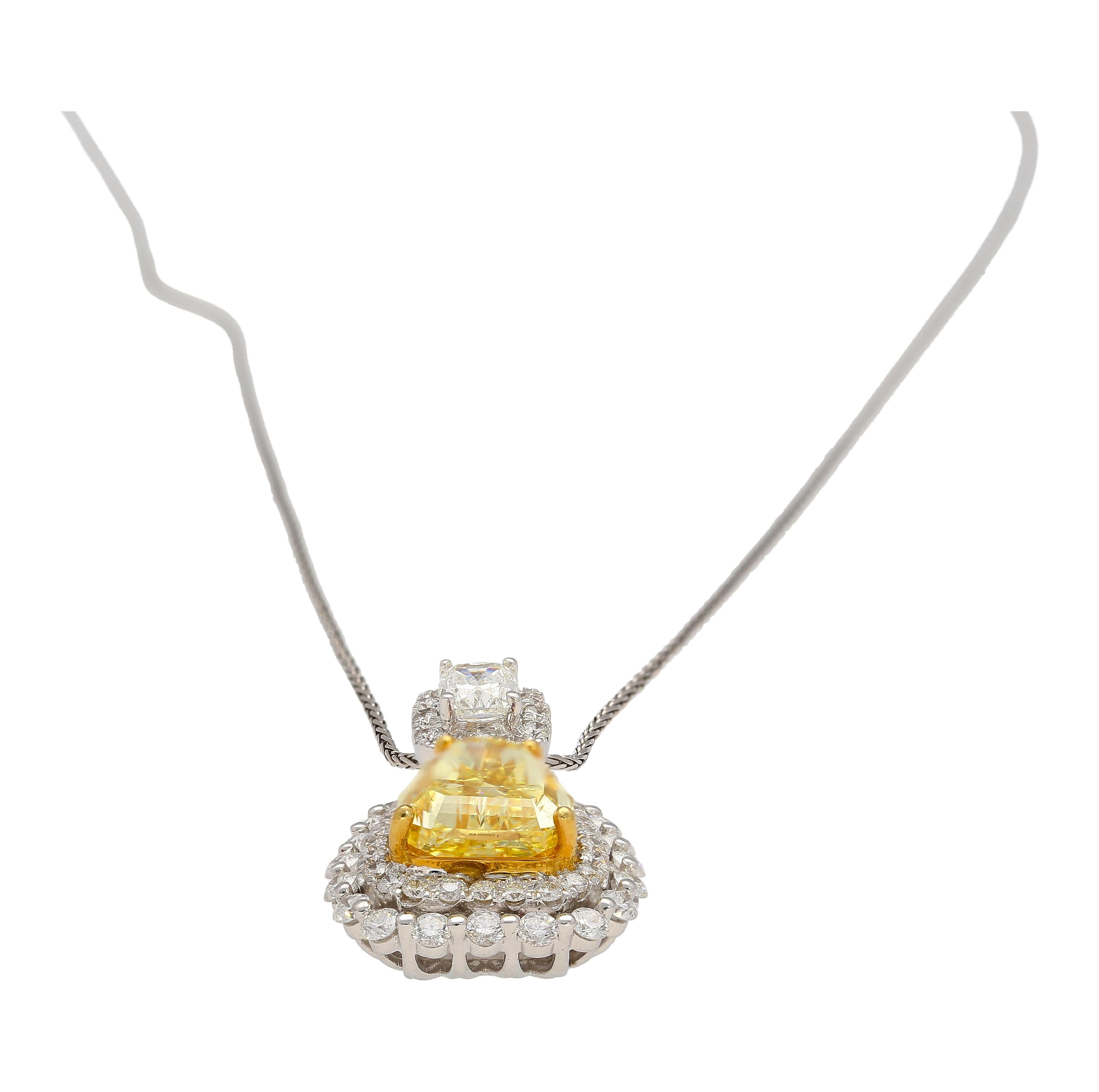 Indulge in the beauty and rarity of this natural GIA certified 3.28-carat Fancy Intense Yellow Shield Cut Diamond pendant with multi-colored diamond side stones, expertly crafted in 18K White and Yellow Gold. Featuring 58 round-cut diamond accents