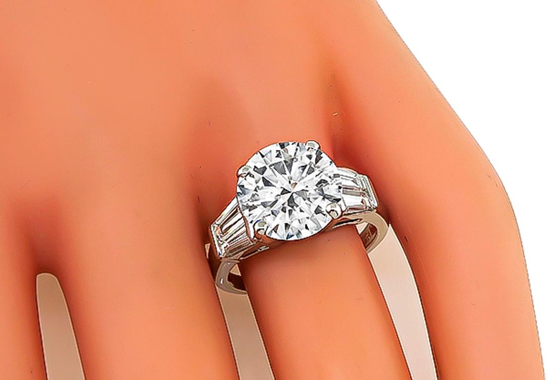 This amazing platinum engagement ring is set with sparkling GIA certified round brilliant cut diamond that weighs 4.00ct. graded E color with I1 clarity. Accentuating the center stone are dazzling baguette cut diamond accents. The ring is stamped