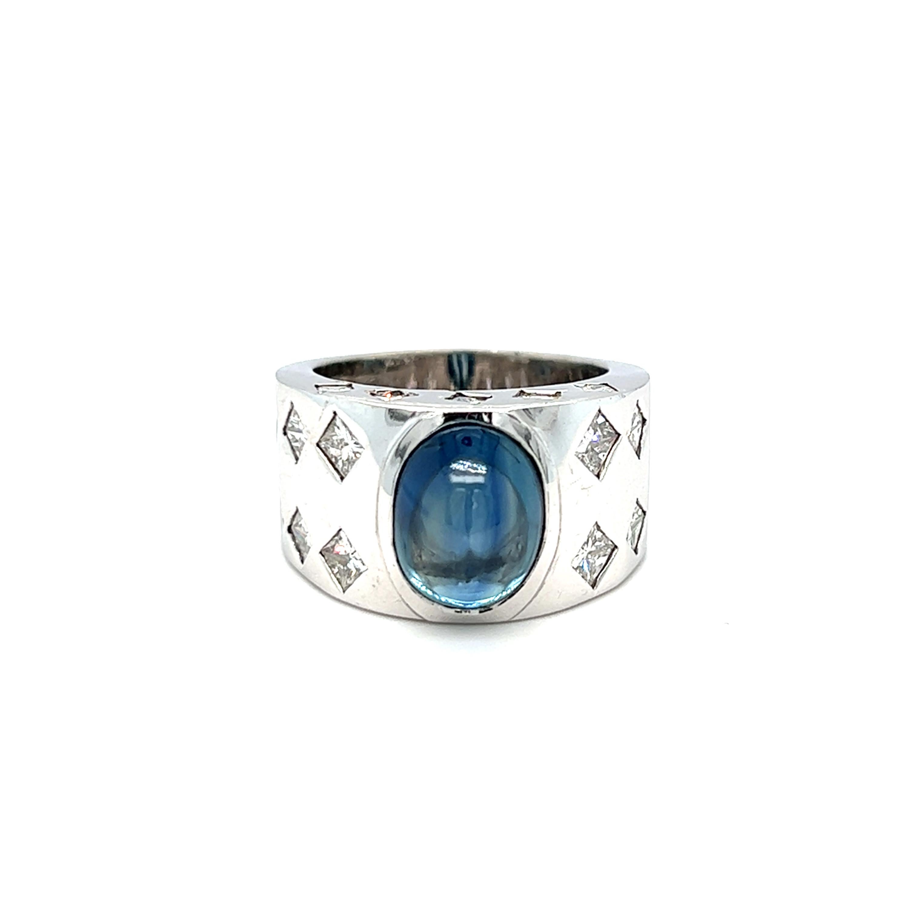 This bold and substantial wide band ring features a GIA certified cabochon sapphire at center. The sapphire measures 11.40 x 9.45 x 7.20 mm and weighs approximately 9 carats. Twenty two square colorless diamond beautifully accent the ring at