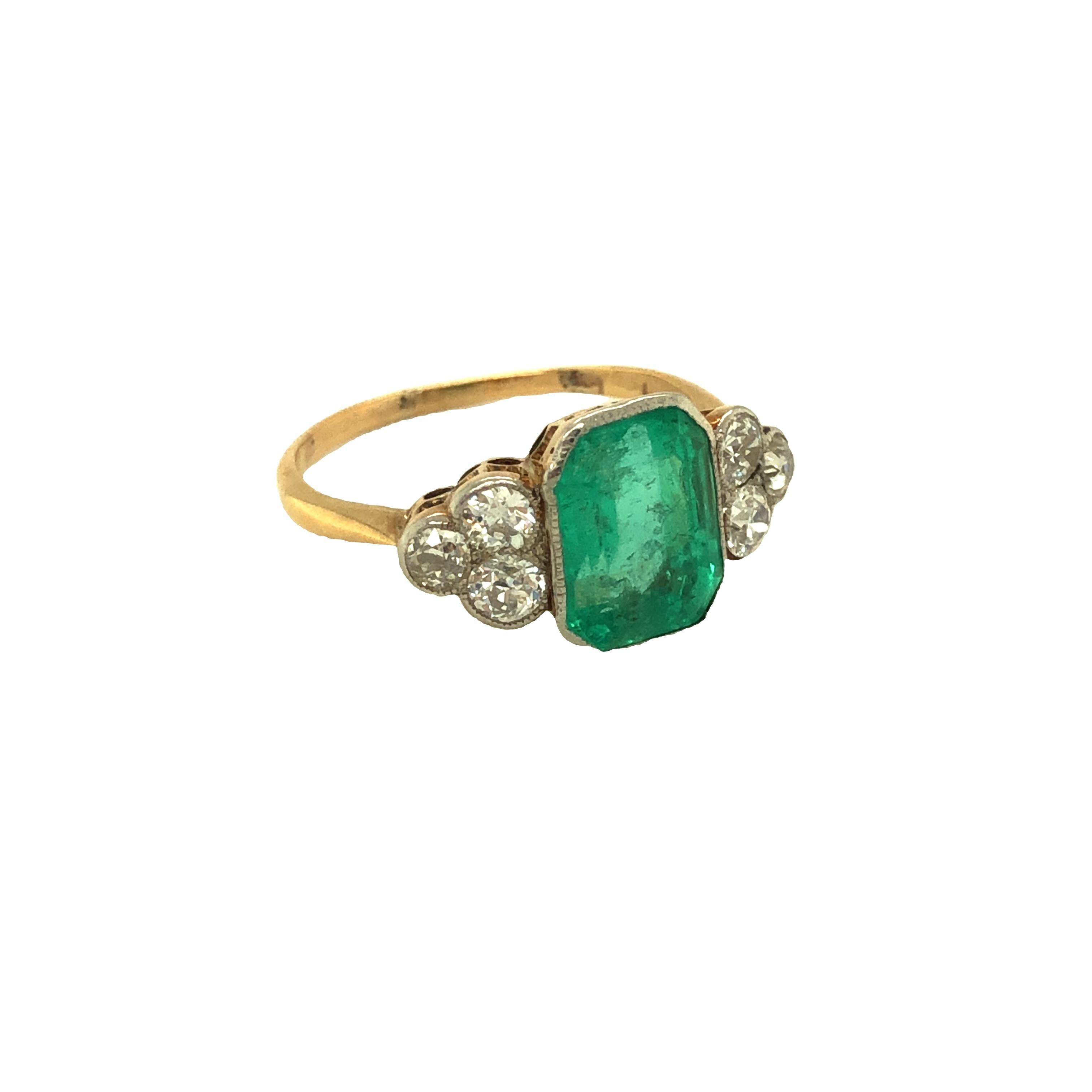 Dieser originelle antike Art-Déco-Ring zeigt einen sattgrünen achteckigen Smaragd im Stufenschliff mit einem Gewicht von etwa 3 Karat (9,45 x 7,20 x 5,12 mm).  Der Ring ist auf jeder Seite mit einer Maserung versehen und wird auf jeder Seite von