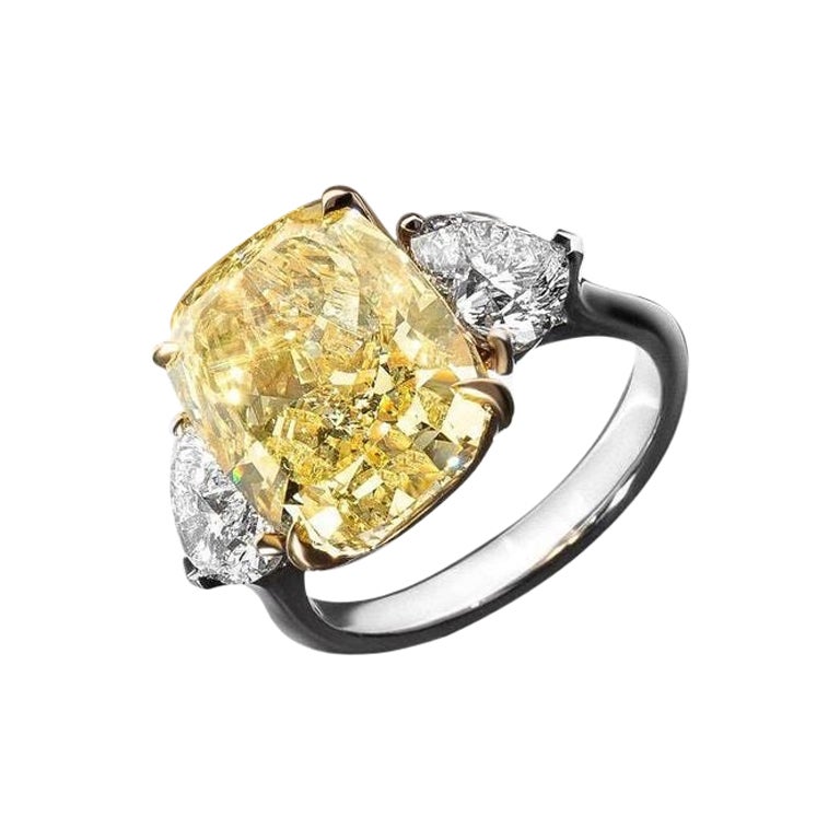 This exquisite ring features a GIA-certified 5.24-carat fancy yellow cushion-cut diamond, elegantly set in 18K white gold, with the upper portion supporting the central stone crafted in 18K yellow gold. 

The vibrant fancy yellow diamond captivates