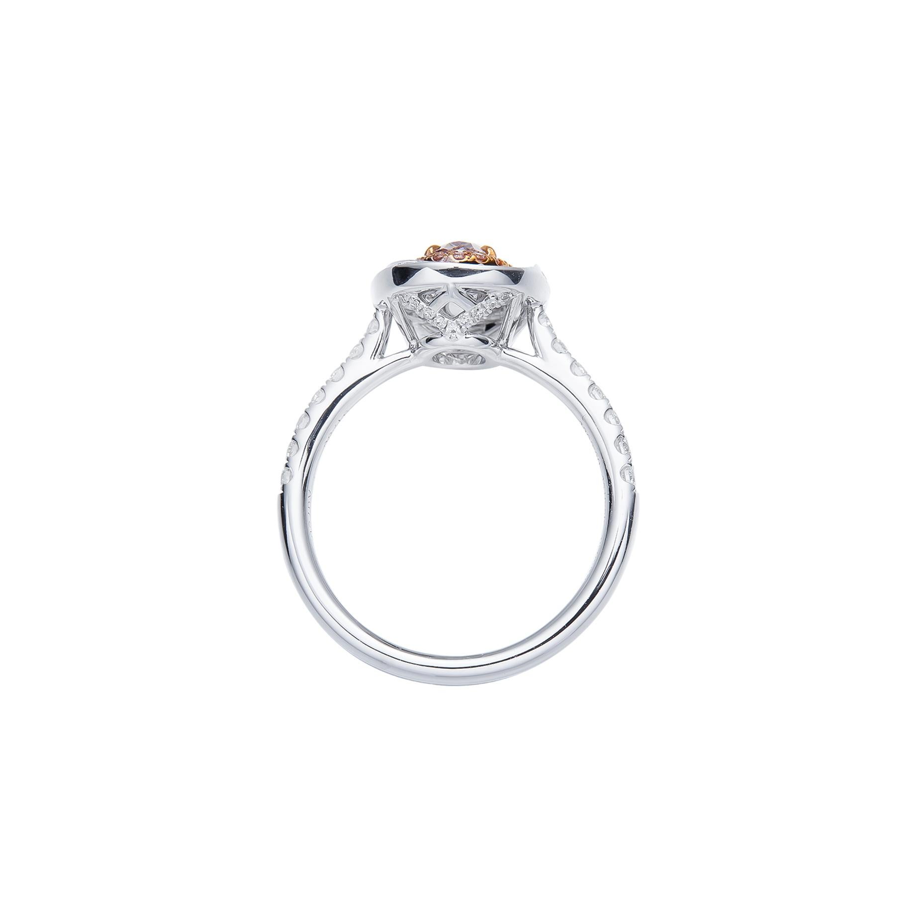 This exquisite natural diamond engagement ring showcases a captivating fancy brownish pink diamond as its centerpiece. Surrounded by a halo of sparkling white diamonds, this oval-cut stunner is set in a timeless White Gold band, adorned with
