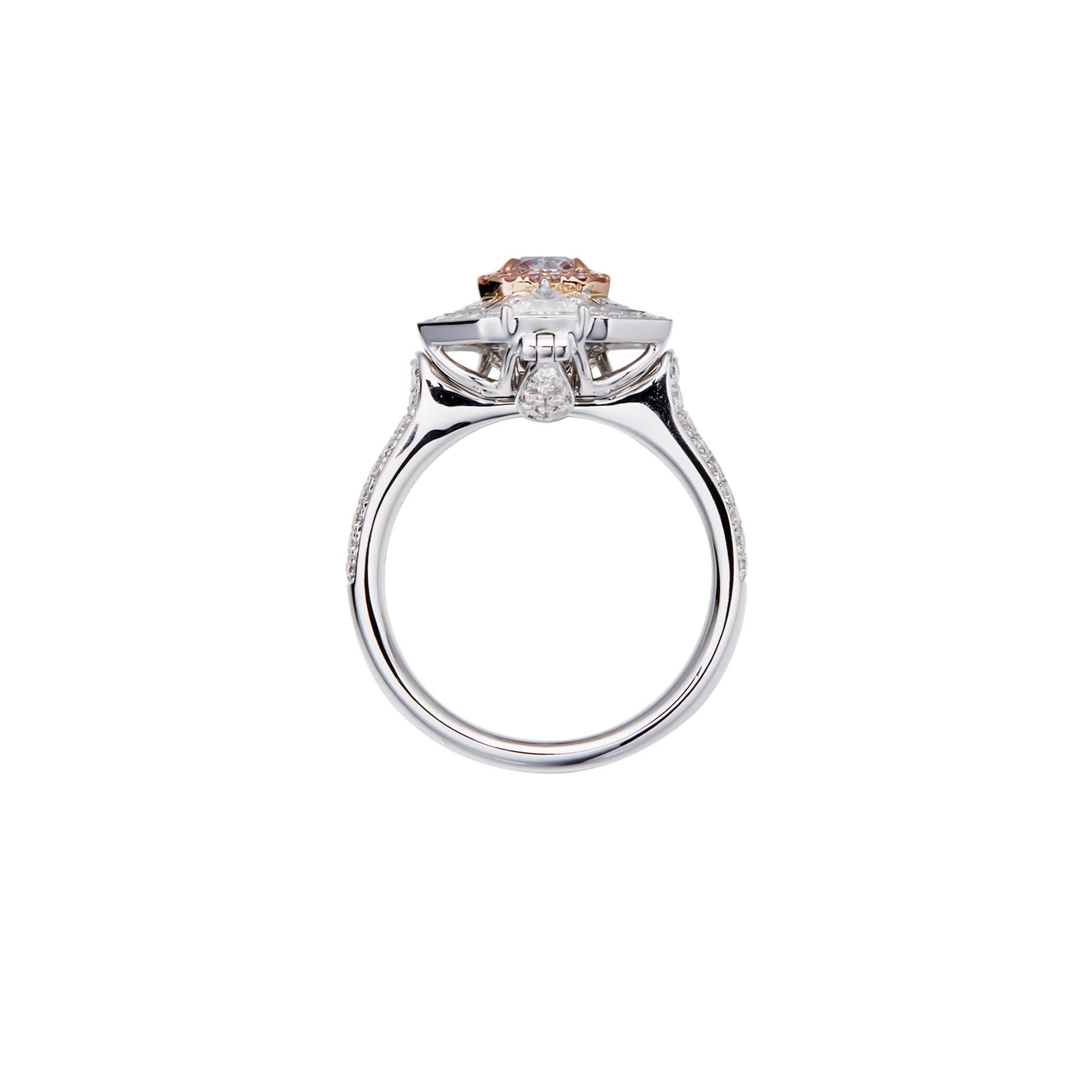 Un impresionante diamante rosa de 0,71 quilates, montado en oro de 18 quilates de alta calidad. El diamante rosa está rodeado por un halo de pequeños diamantes redondos brillantes de color rosa natural, que añaden profundidad y brillo al