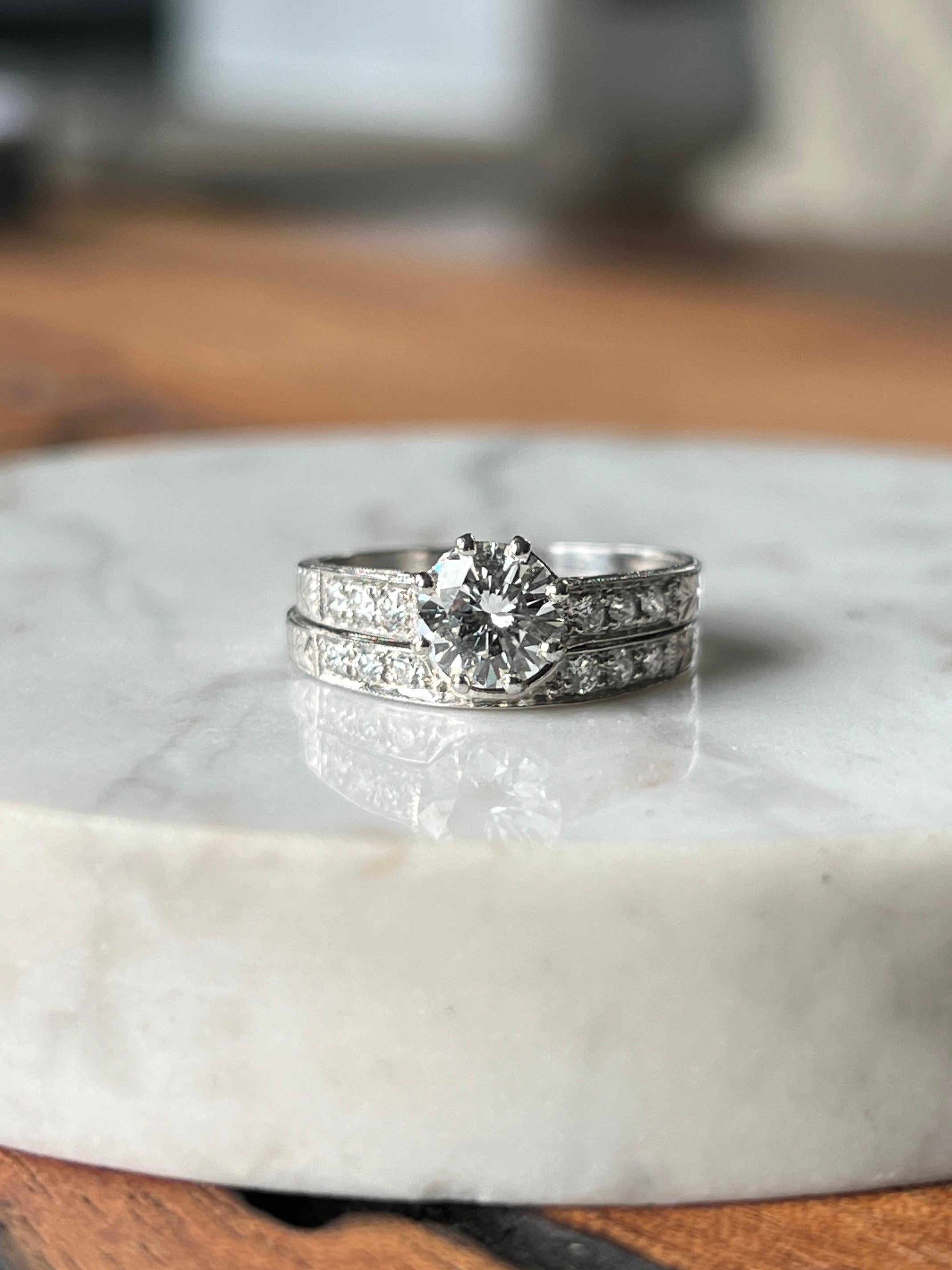 This estate 18 karat white gold Art Deco-inspired wedding set features a timeless design with intricate filigree details. The engagement ring is set with a 0.83-carat round brilliant diamond, graded G/SI1, with a GIA report (#1221338) center stone.