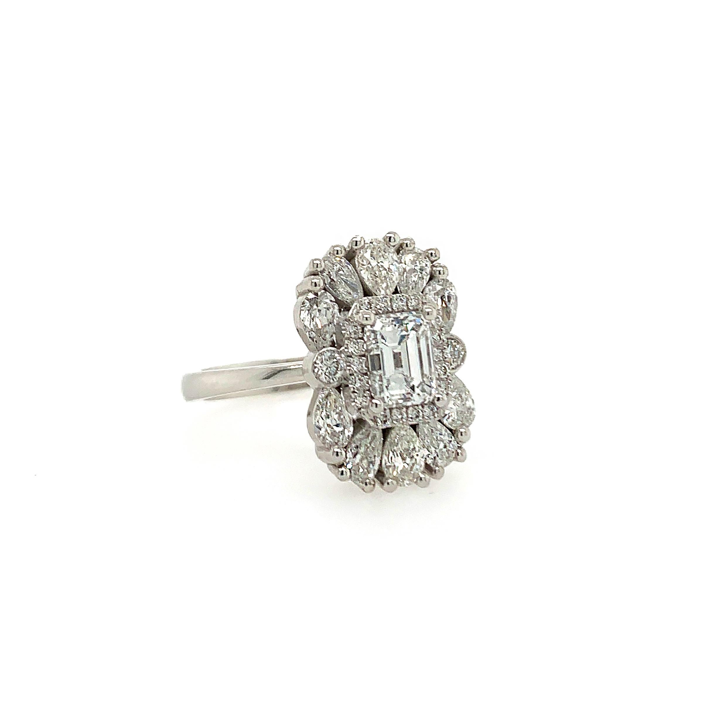 This beautiful ring flaunts a 0.85 carat emerald-cut natural white diamond surrounded by a diamond halo and set atop a bed of 10 pear-shaped white diamonds and 2 bezel set round brilliants. The tapered white gold shank adds a touch of elegance to