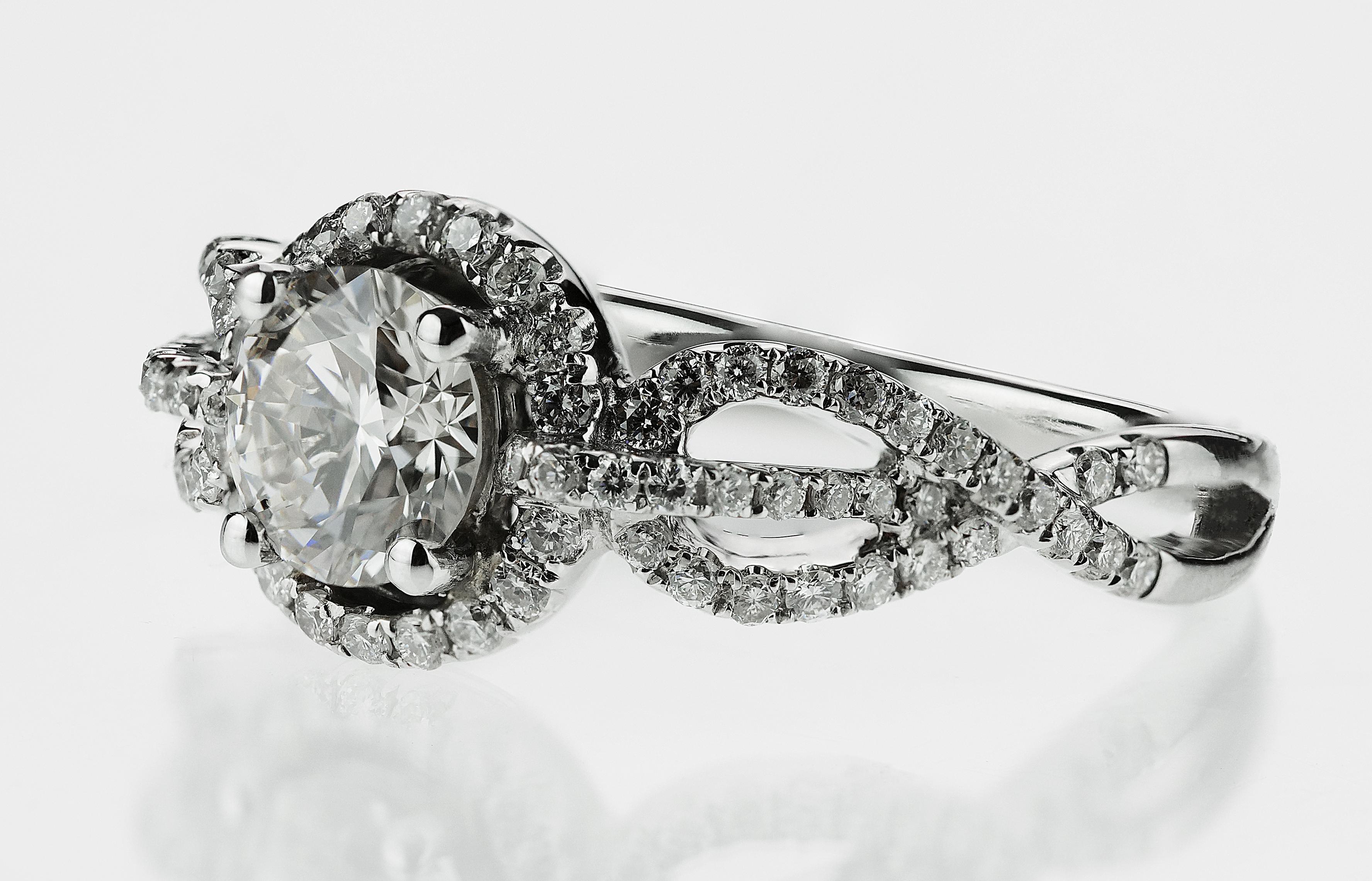 Exquisiter Ring aus 18 Karat Diamant und Weißgold, bestehend aus einem runden Brillanten in der Mitte mit einer erhabenen Diamantbordüre und zwei Schultern mit atemberaubenden Unendlichkeitssymbolen, die zur Hälfte mit Diamanten besetzt sind und
