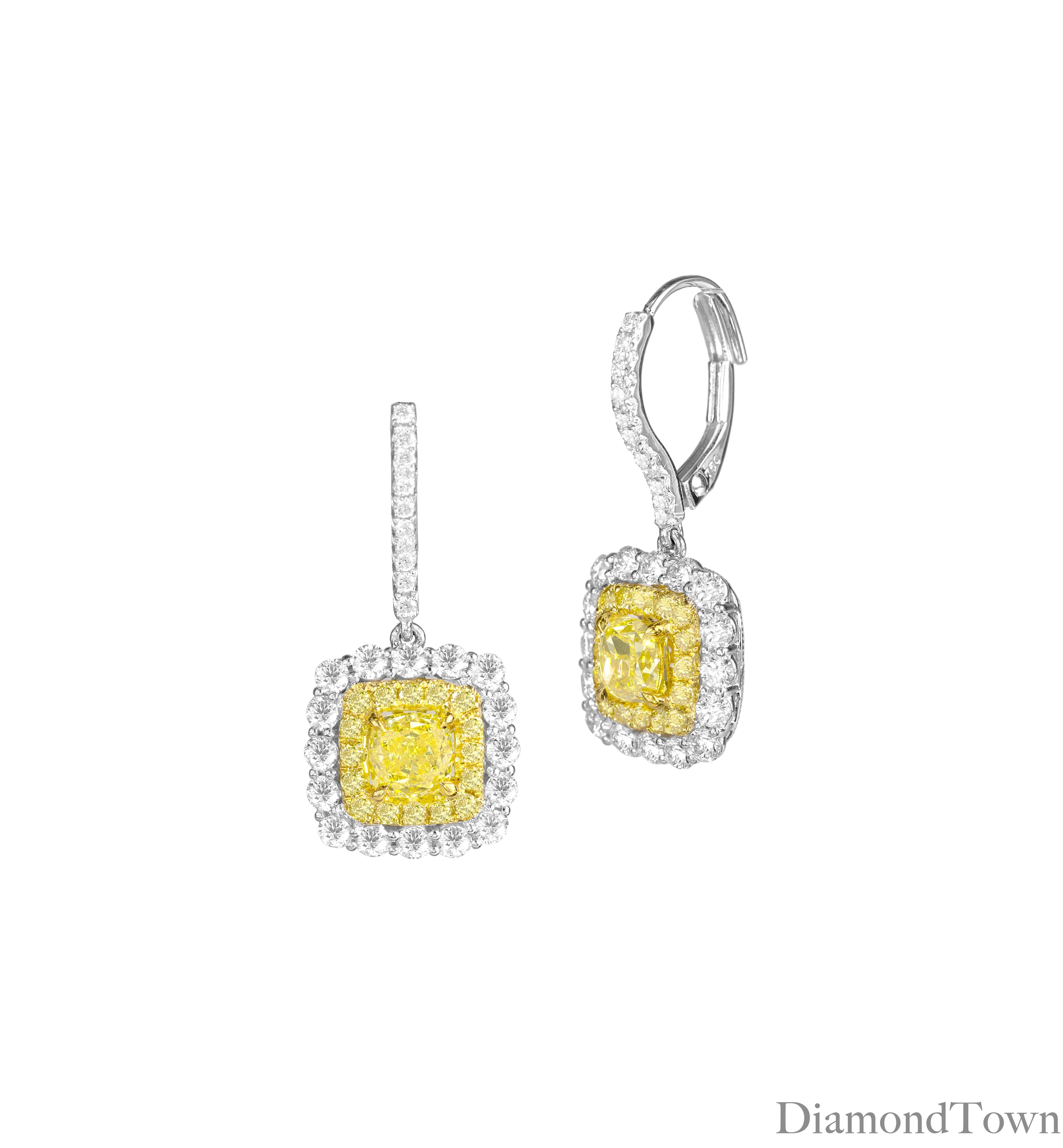 These exquisite earrings feature GIA Certified Oval Cut Natural Fancy Intense Yellow diamonds at the center, measuring 0.86 and 0.79 carats, beautifully encircled by a double halo of round yellow and round white diamonds. They are securely set on