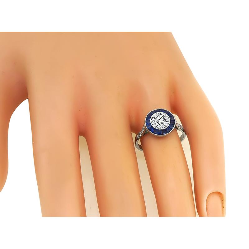 This is an elegant platinum engagement ring. The ring is centered with a sparkling GIA certified old European cut diamond that weighs 0.93ct. The color of the diamond is I with VS2 clarity. The center diamond is accentuated by sapphire and diamond