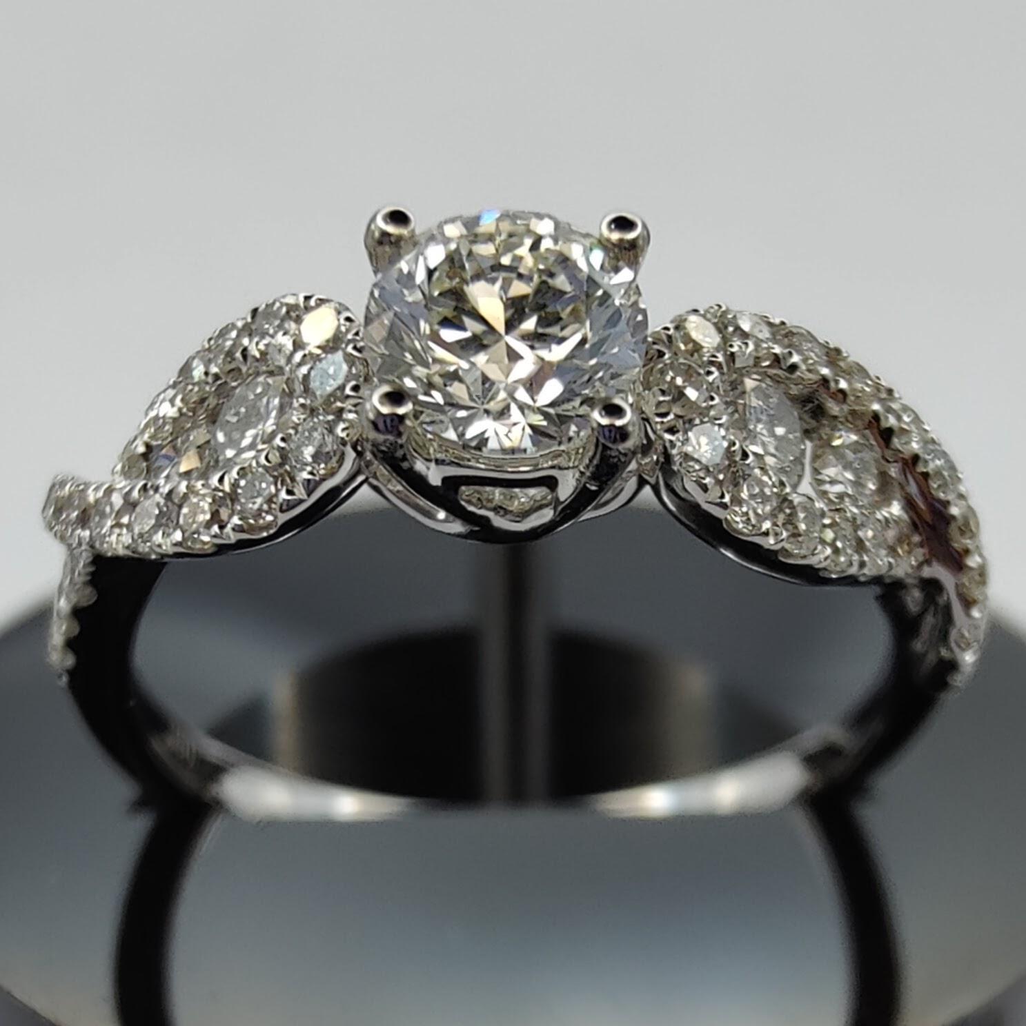 This gorgeous engagement ring is inspired by angel wings and features a stunning center diamond accompanied by two diamond wings. The round diamond at the center weighs 0.93ct and is GIA certified. The diamonds on the wings are expertly set in
