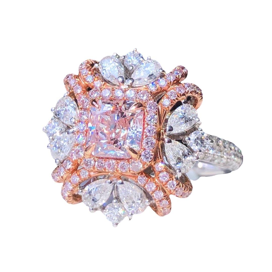 We invite you to discover this majestic ring set with a 1 carat GIA certified Very Light Pink cushion-cut diamond enhanced with a halo of pink diamonds and pear-shaped colorless side diamonds weighing 1.7 carats in total. The wonderful surprise is