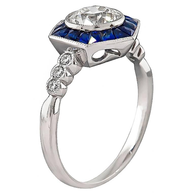 This charming platinum engagement ring is centered with a sparkling GIA certified old European cut diamond that weighs 1.00ct. graded J color with SI2 clarity. The center diamond is accentuated by lovely sapphire and diamond accents.
The ring is