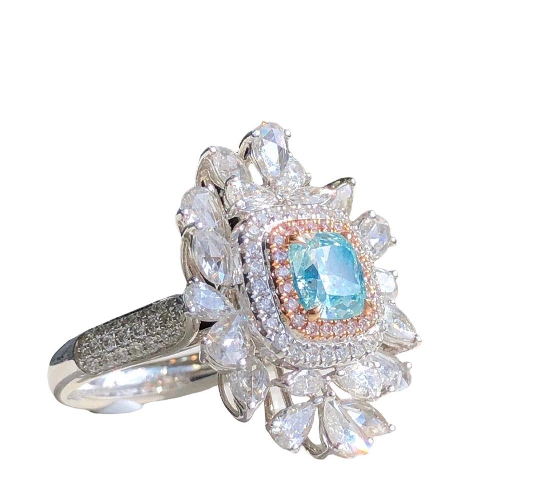 Nous vous invitons à découvrir cette bague de cocktail unique sertie d'un diamant bleu clair taille coussin de 1,15 carat certifié par la GIA, rehaussé d'un double halo de diamants incolores et roses agrémenté de diamants multi-tailles totalisant