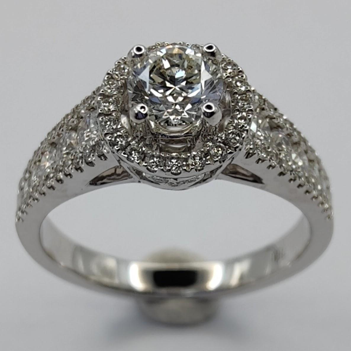 This stunning GIA certified diamond ring is the perfect choice for your special day. The ring features a sparkling 1 carat round cut diamond set in a cathedral pave design, surrounded by a halo of smaller diamonds. The ring is made of 18K white