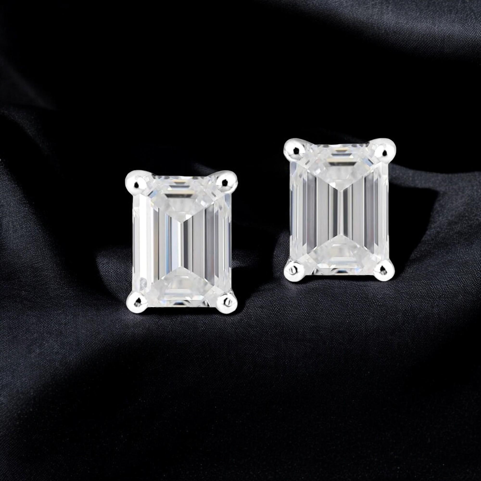Add a touch of elegance to your outfit with these stunning stud earrings. Crafted with 18k white gold, these earrings feature a beautiful emerald-shaped diamond with a total carat weight of 1 ct [0.50 ct each], accompanied by two sparkling diamonds.