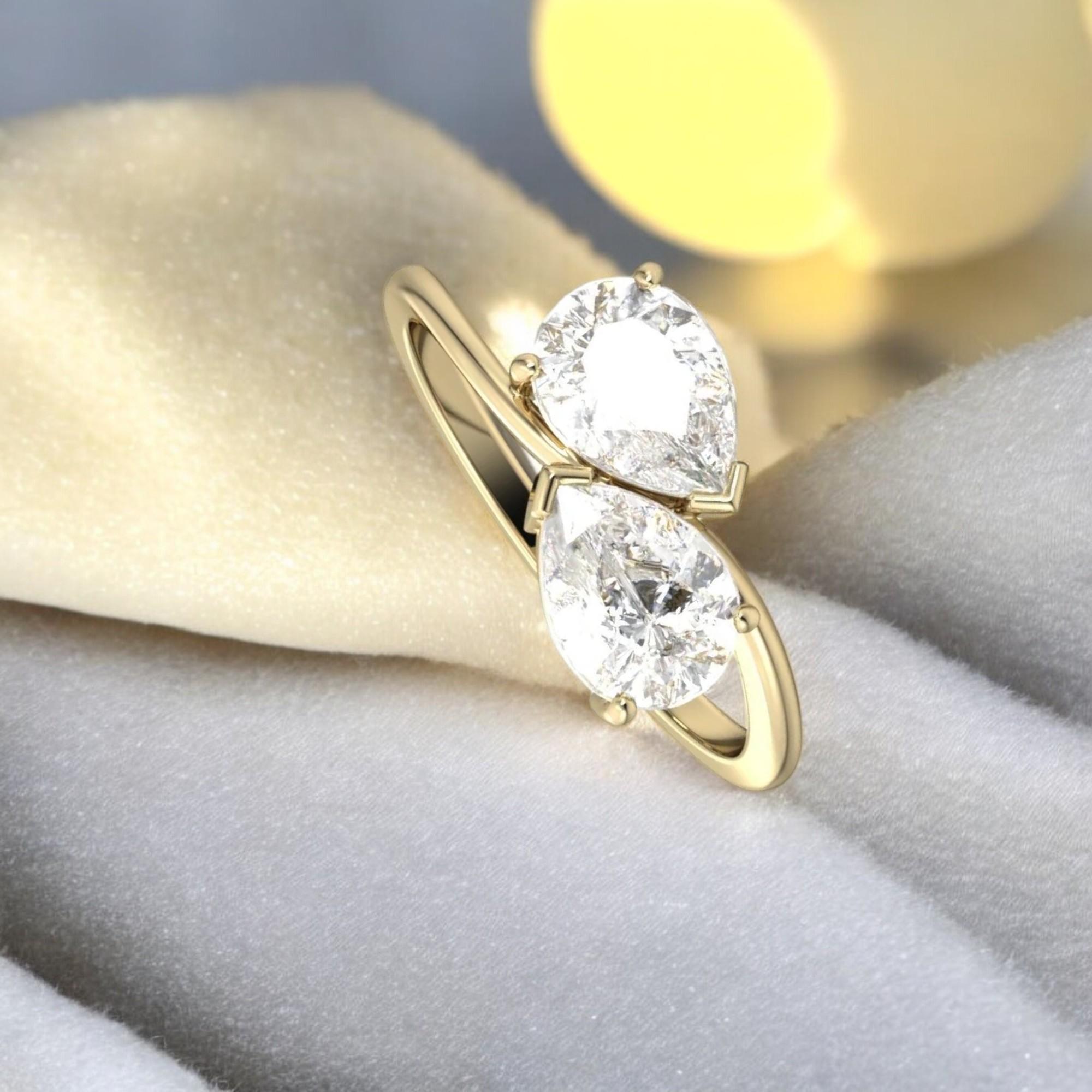 Questo splendido anello di fidanzamento presenta un bellissimo diamante a forma di pera in una montatura a due pietre. L'anello è realizzato in oro 18 carati di alta qualità e ha un peso totale di 1 carato (0,50 carati ciascuno). I diamanti sono