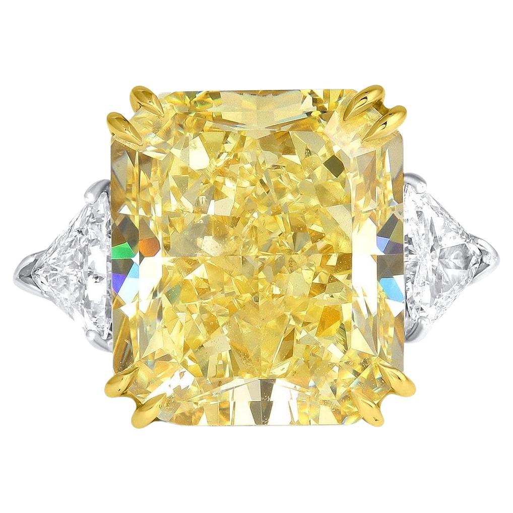 This exquisite ring features a stunning GIA certified 10.44 carat radiant cut diamond in a captivating Fancy Yellow hue. The diamond boasts an VVS2 clarity  Complementing this magnificent center stone are two trapezoid white diamonds on either side,