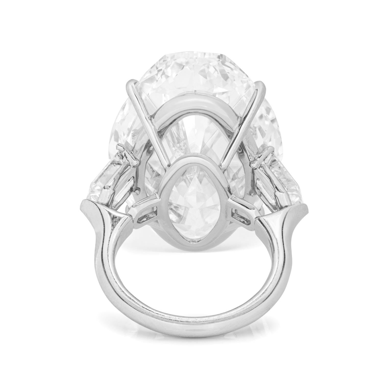 This stunning platinum ring showcases a remarkable 10-carat oval-cut diamond as the centerpiece, flanked by beautifully matched trapezoid diamonds on either side, creating a sophisticated and balanced design. The center diamond, certified by GIA,