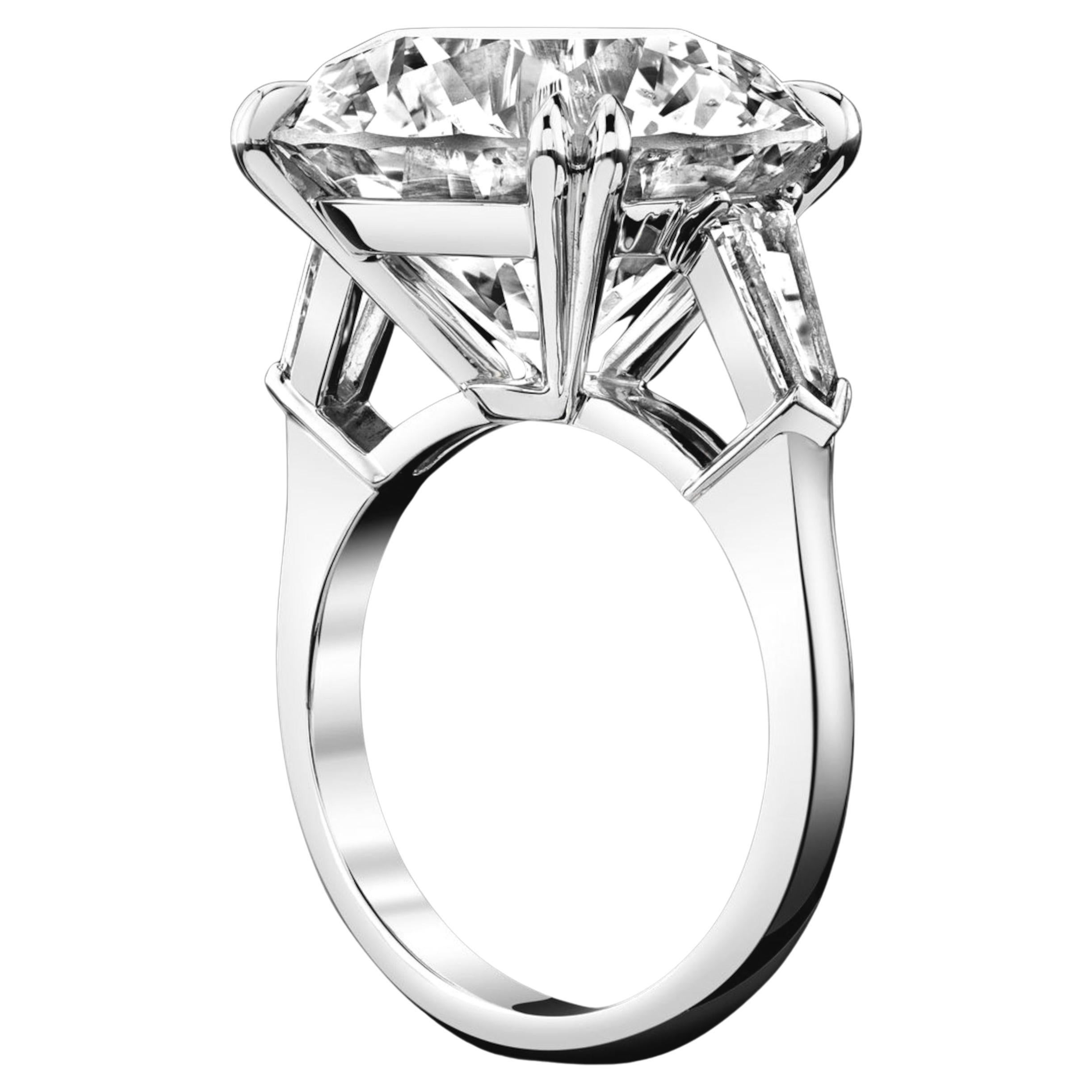 This magnificent three-stone ring showcases a stunning 10.05 carat round brilliant cut diamond at it's center, flanked by two tapered baguette diamonds, all set in a sophisticated platinum design. 
The tapered baguette side stones complement the