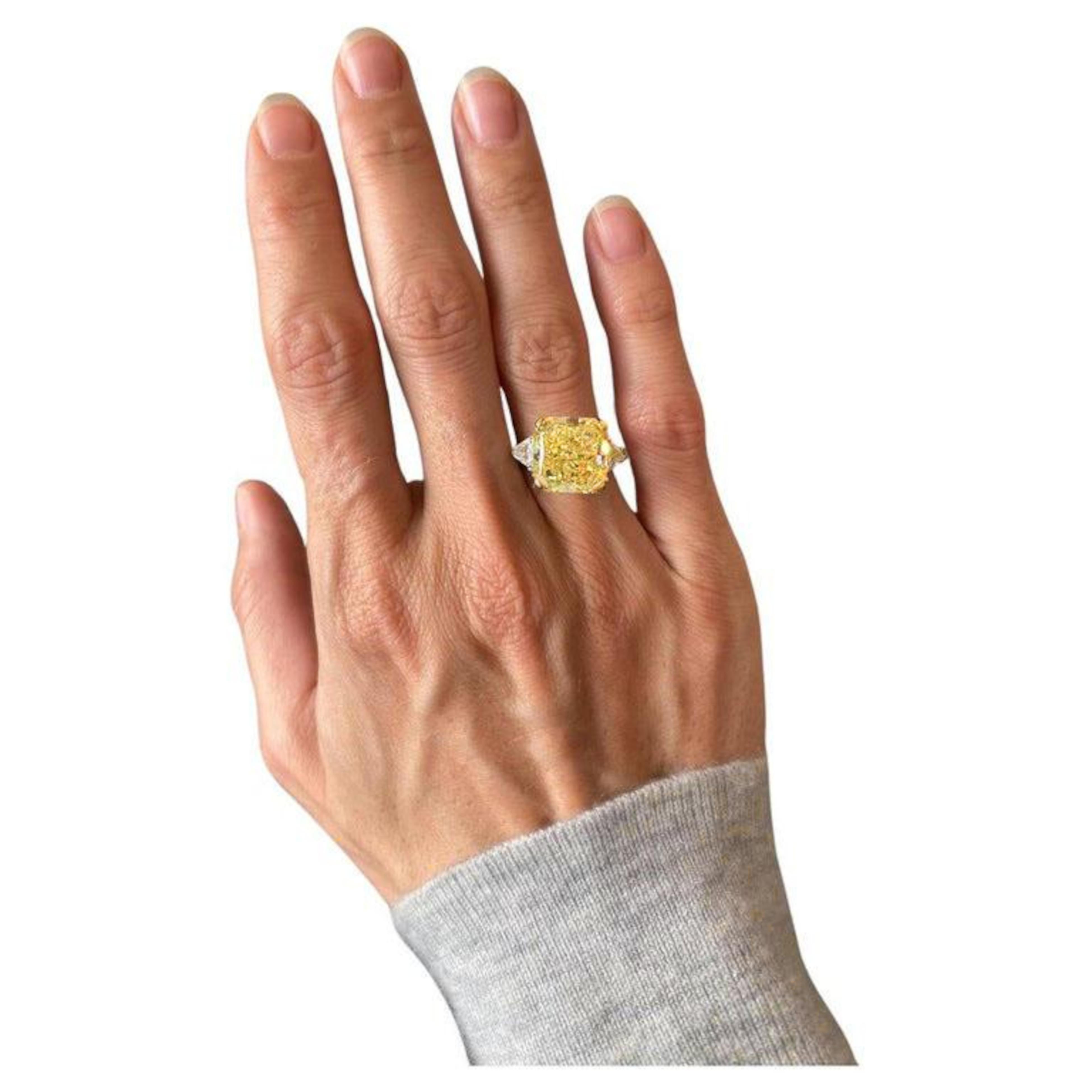 10 ct total weight radiant cut natural yellow diamond three-stone engagement ring is a stunning piece that combines platinum and 18K yellow gold. The centerpiece is a 10 ct natural radiant cut diamond, fancy yellow color which presents a lovely 