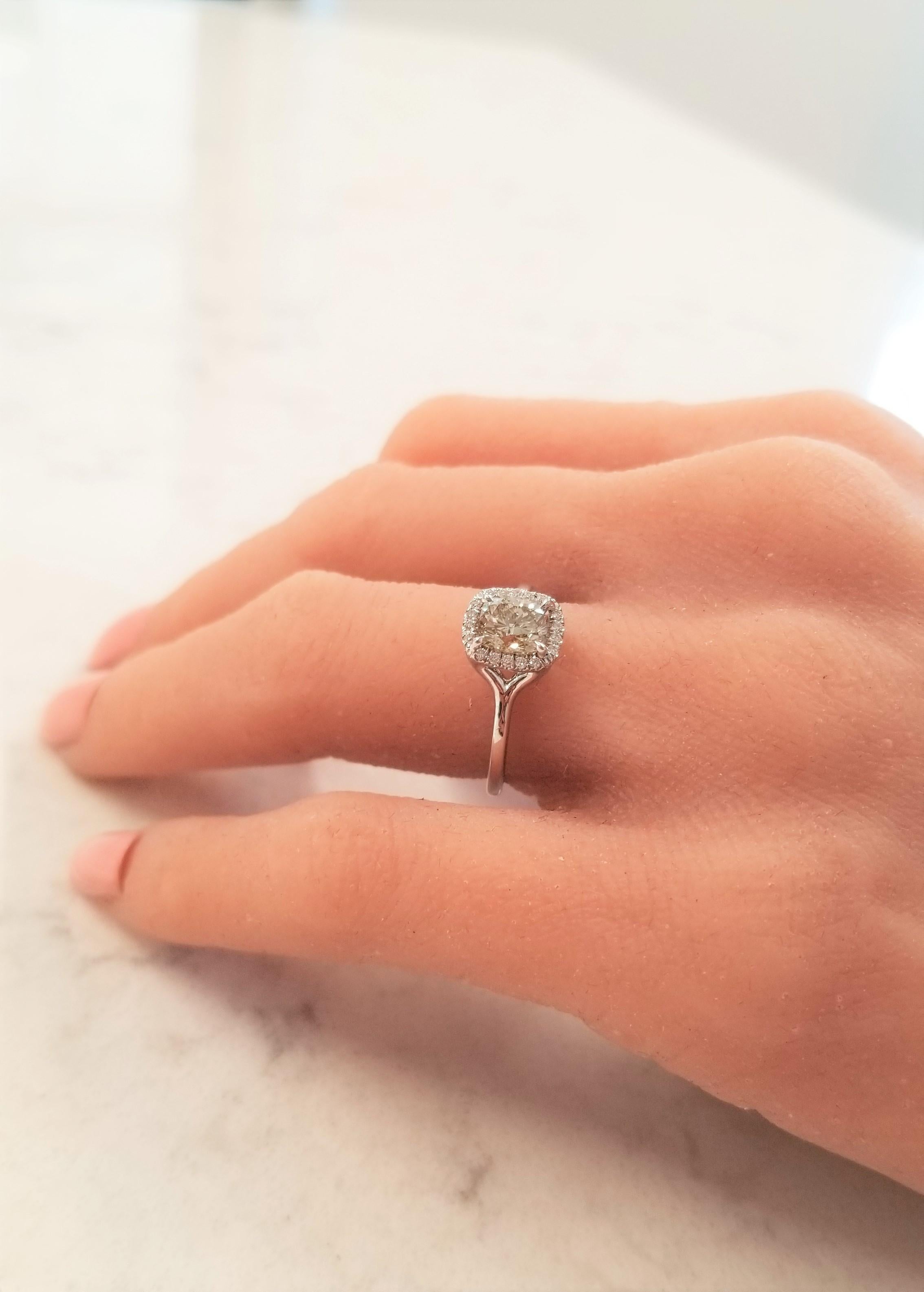 Simple never looked so stunning! This is an 18k white gold solitaire ring, which features a GIA certified light brownish-greenish yellow cushion-cut 1.00 carat center diamond. Then the style is kicked up a notch with 0.12 carat of brilliant diamonds