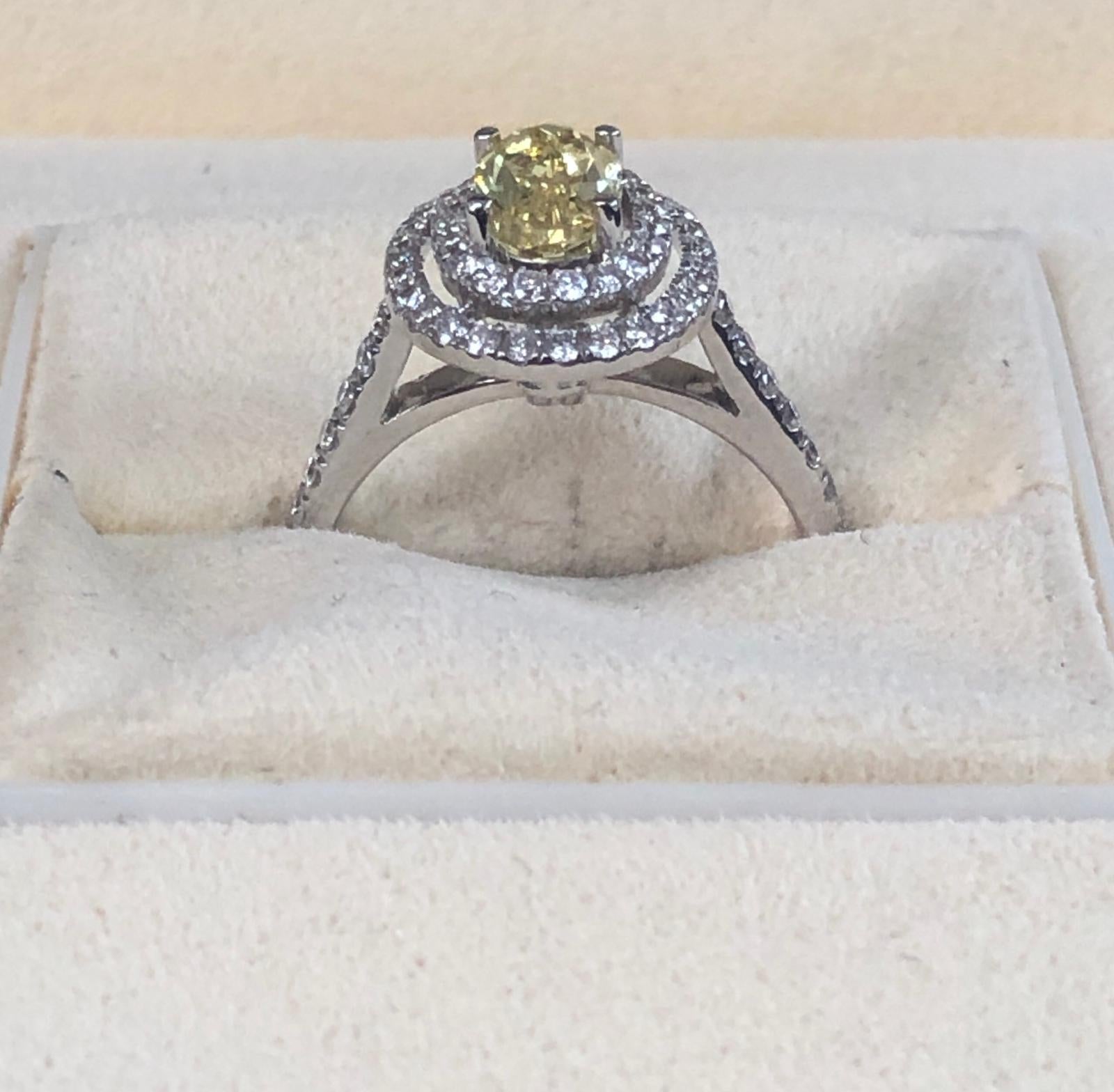 Natural Fancy Vivid Yellow oval diamond weighing 1.00 carats by GIA.  Half way paved white diamonds in the double halo setting. Its transparency and luster are excellent. set on 18K white gold, this ring is the ultimate gift for anniversaries,