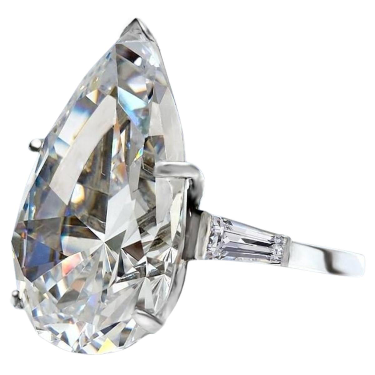 Adorn yourself with the unparalleled elegance of this GIA Certified 10.01 Carat Pear Cut Diamond Ring, accentuated by tapered baguette diamonds. At the heart of this exquisite ring gleams a stunning pear-cut diamond of extraordinary quality,