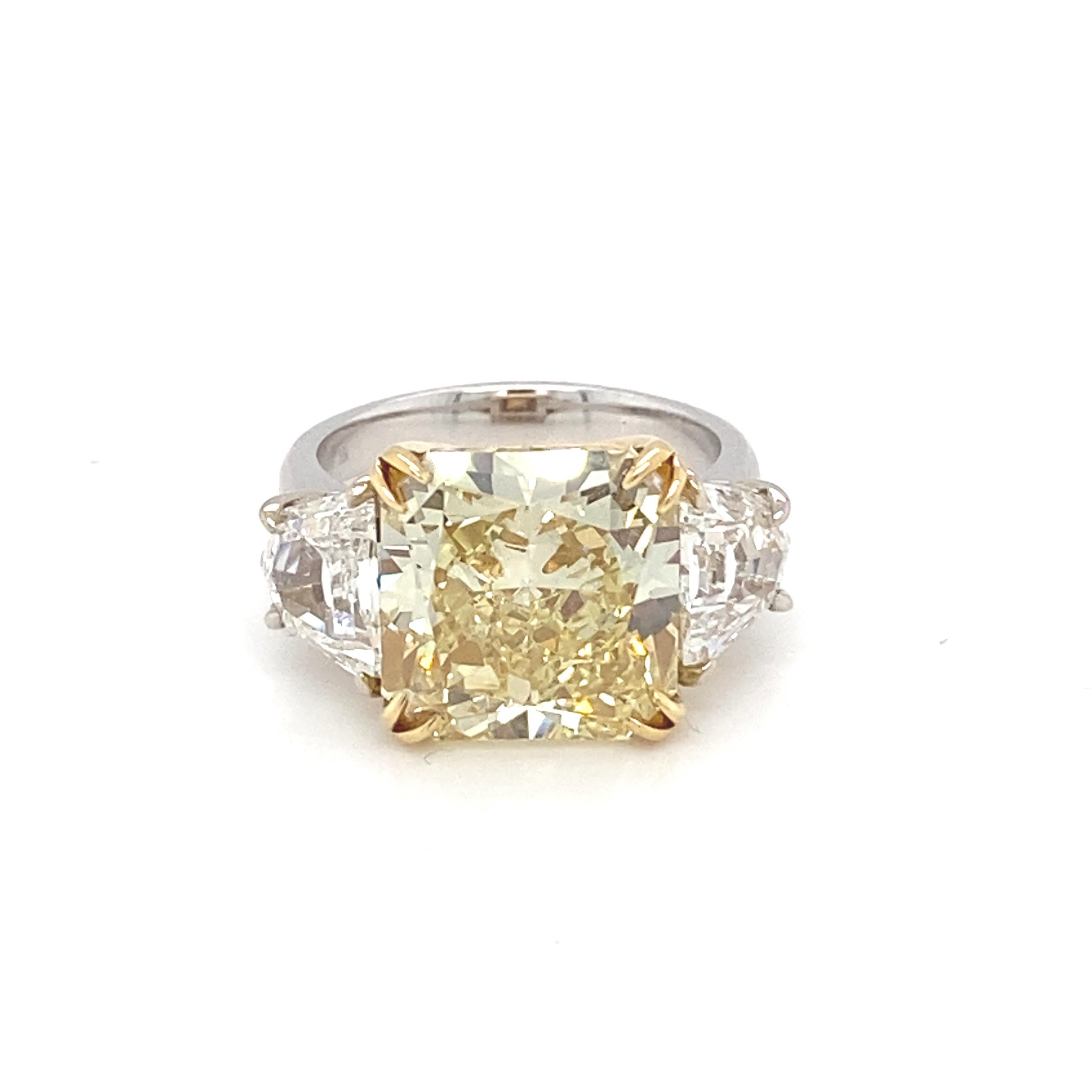 Dieser prächtige Ring rühmt sich mit einem GIA-zertifizierten 10,03 Karat Fancy Intense Yellow Kissenschliff-Diamanten als Mittelstein mit zwei trapezförmigen weißen Diamanten als Seitenstein. Der Mittelstein ist in Gelbgold gefasst, während die