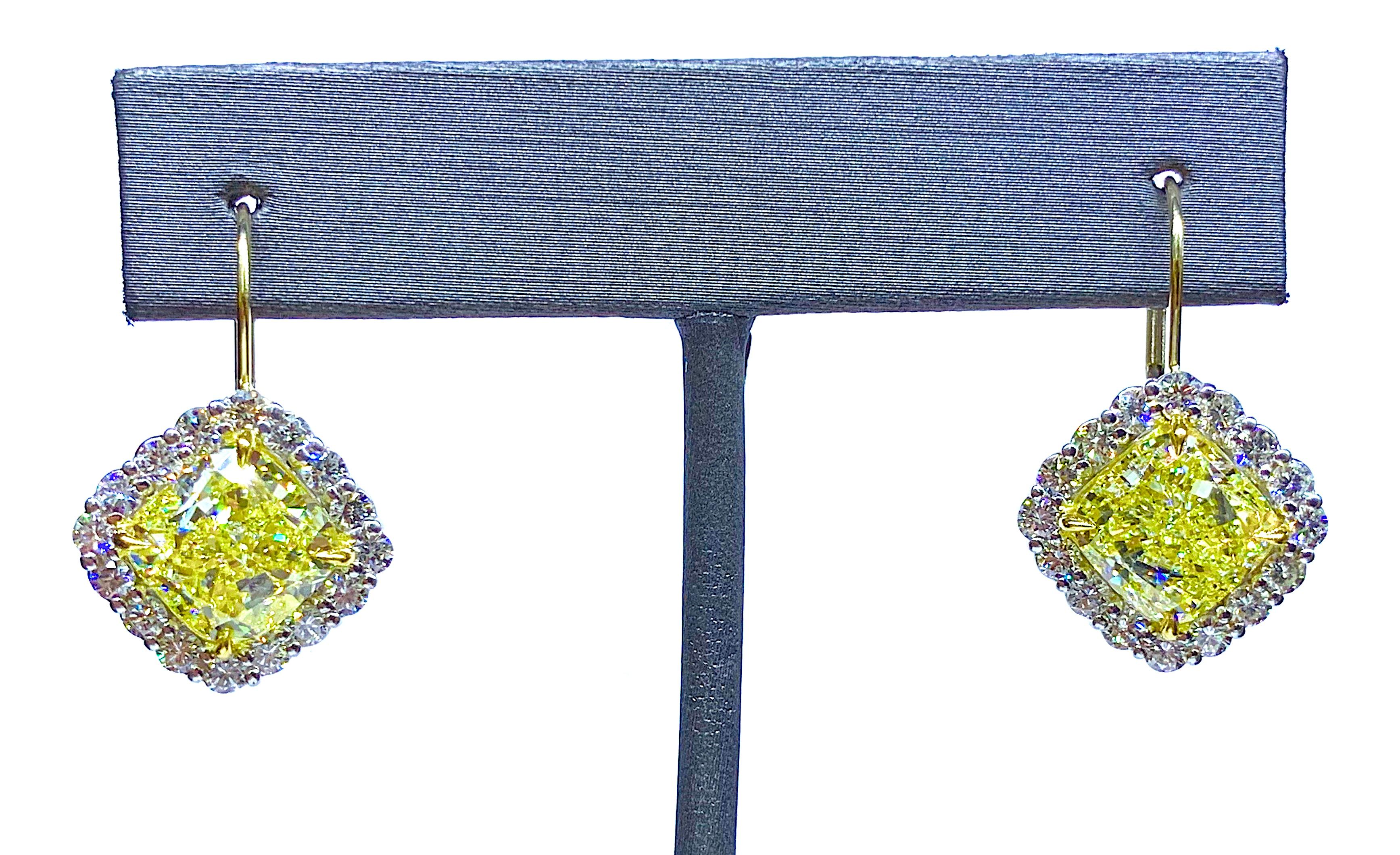       Remarkable matching pair of Fancy Yellow Diamond earrings. To find two Diamonds of the same size and most importantly matching color is extremely rare. This pair is highlighted with a pair of matching Cushion Brilliant Cut Diamonds weighing