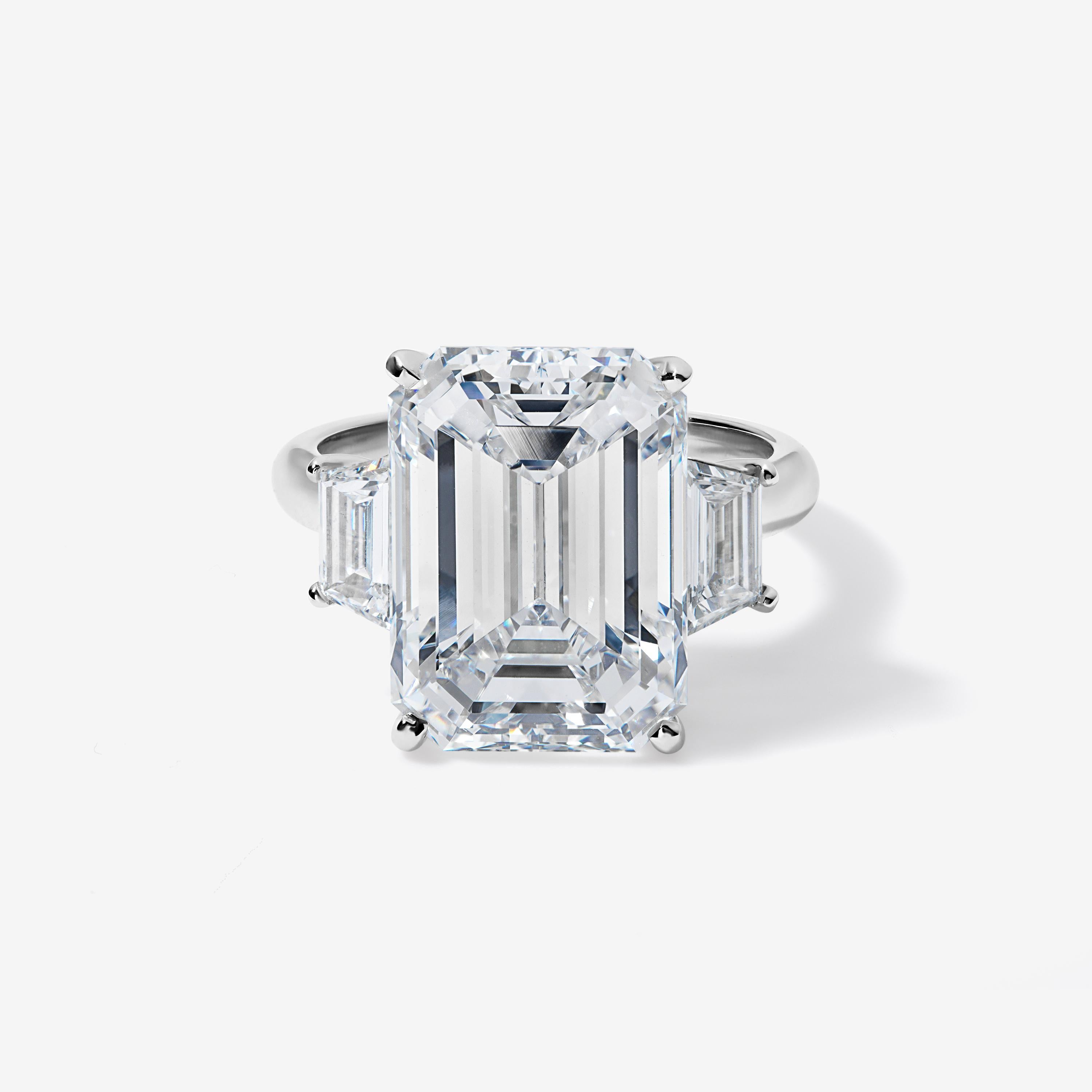 This platinum three stone ring is as classic as it gets.

The center 10 carat emerald cut diamond is colorless and eye clean, with an ideal 1.37 ratio and excellent polish and symmetry. It sits between two trapezoid cut diamonds, which are