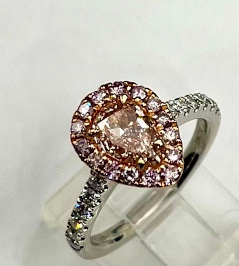 Cette bague de style classique présente un diamant rose naturel de 1 carat entouré d'un halo de diamants roses naturels.  Bien que le rapport GIA indique la présence d'une couleur secondaire brune, celle-ci ne semble pas affecter la teinte rose du