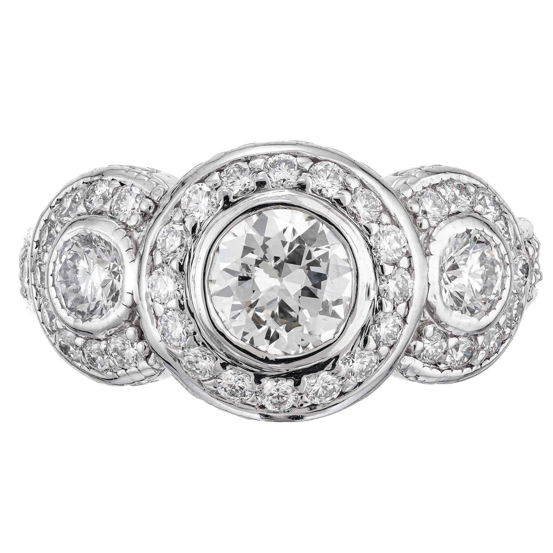 Three stone triple halo diamond ring with engraved sides and shoulders. The center diamond is GIA certified. Set in 14k white gold three stone setting with halos around each diamond, accented with round diamonds along the shank.  

1 round brilliant