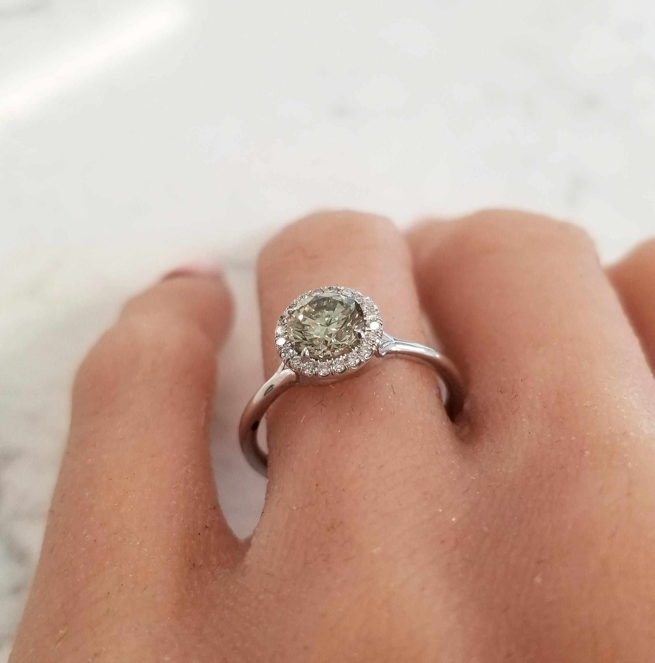 Simple, yet sophisticated and unique. This gorgeous diamond ring is a welcome addition to any ensemble. It features a GIA certified 1.01 carat round natural fancy greyish-greenish yellow diamond in the center that is gracefully accented by a 0.12