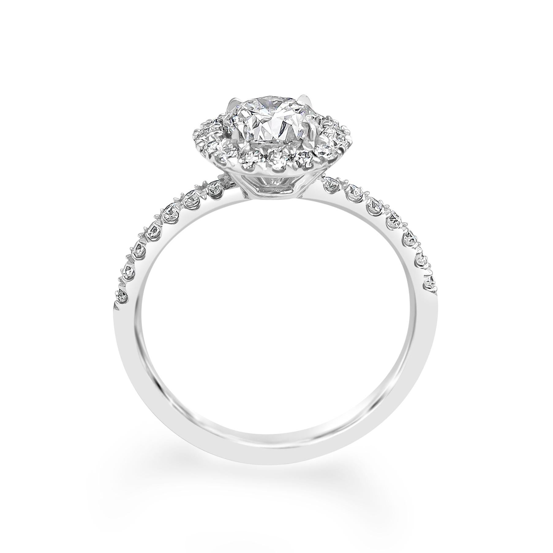 A classic and popular engagement ring style showcasing a 1.01 carat round brilliant diamond, certified by GIA as J color, VS2 clarity. Surrounding the diamond center is a single row of round brilliant diamonds, set on an accented pave mounting.