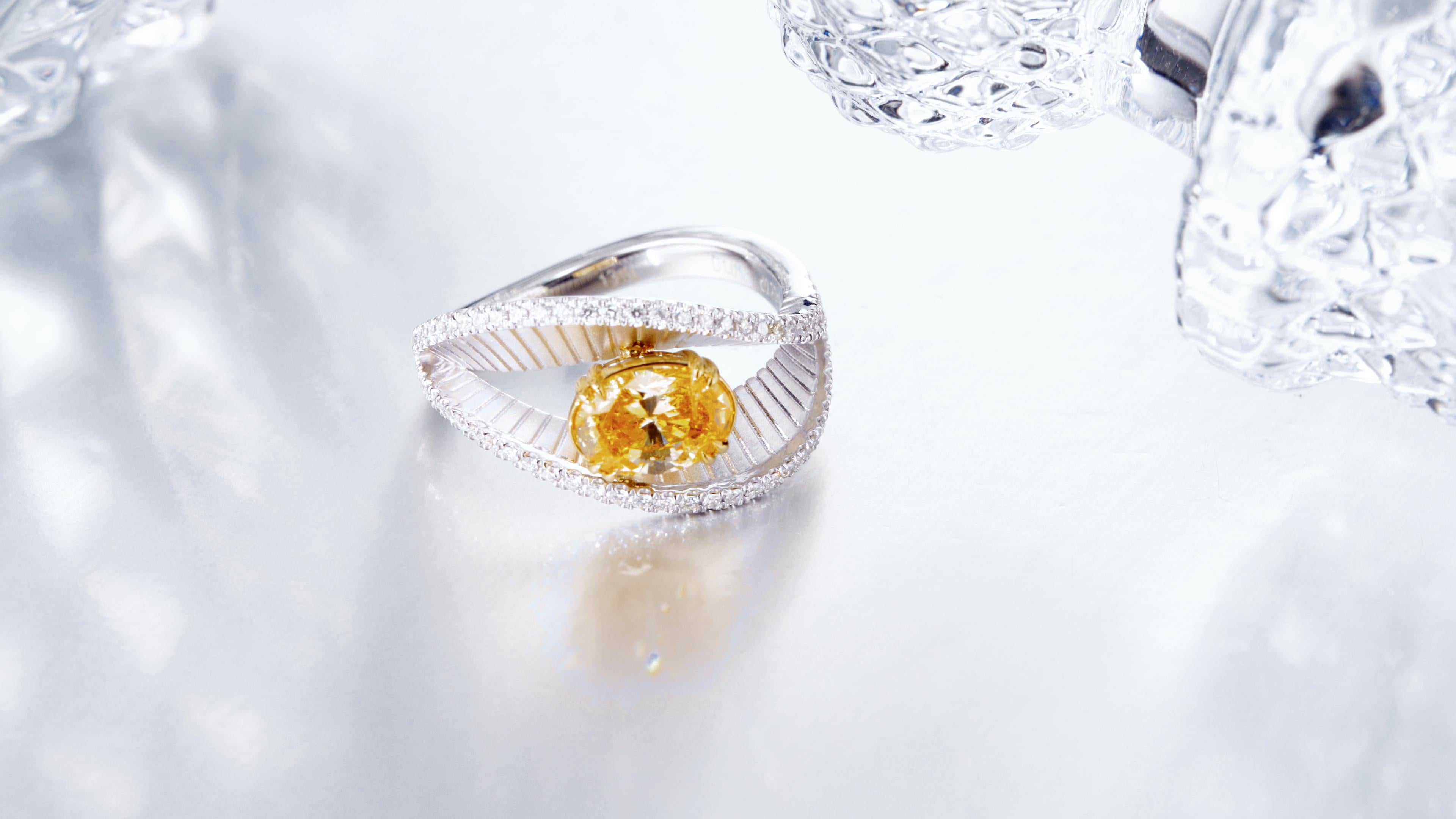 GIA Certified 1.01-carat Natural Fancy Intense Yellow-Orange Oval Diamond Ring set in exquisite 18KT gold. This ring is a testament to rare beauty, featuring a central oval-cut diamond that boasts a captivating blend of intense yellow and orange
