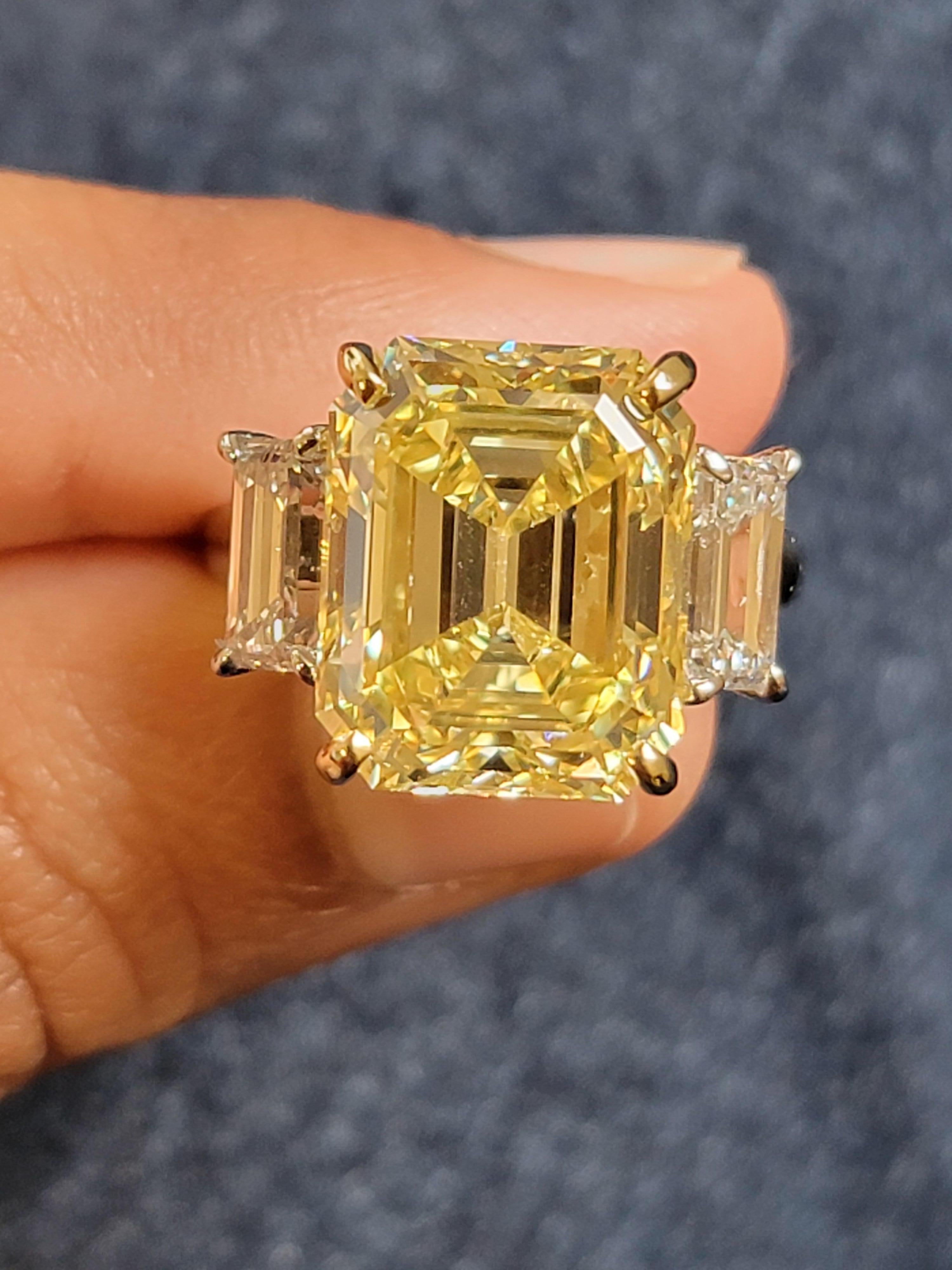 Discover the epitome of elegance with this breathtaking GIA Certified Platinum & 18K YG 10.14 Carat Natural Fancy Intense Yellow Emerald Diamond flanked by two dazzling emerald white diamonds F color & VS clarity ring . Crafted with precision and