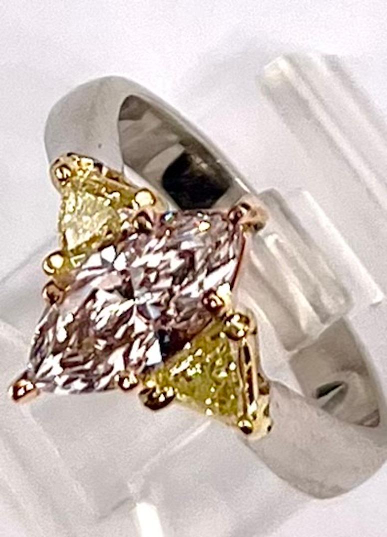 This is a beautiful and simple ring set with a 1.01Ct Natural Very Light Pink Diamond accented by 2 Natural Yellow Triangle Shape Diamonds. The yellow hue very nicely enhances the delicate pink of the diamond without being a distraction.  Pink