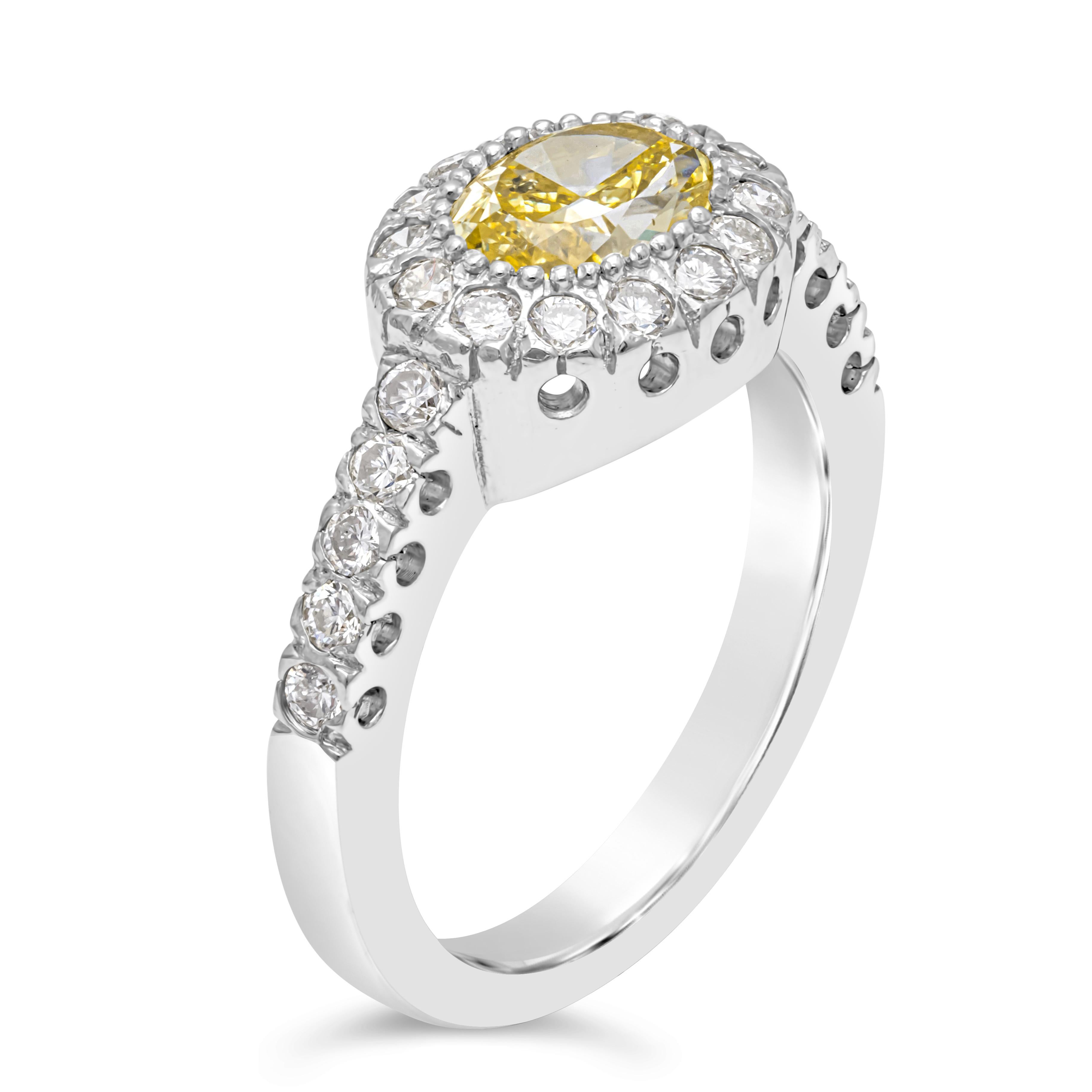 A well-crafted engagement ring, showcasing a GIA certified 1.03 carats oval cut Fancy Yellow diamond. Accented by a beautiful halo of 24 round brilliant cut diamonds that continue on to the shank with a half-way infinity setting, weighing 0.36 carat