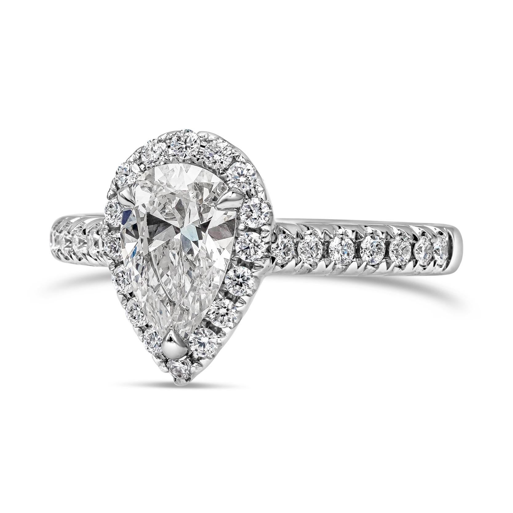 A classic engagement ring style showcasing a 1.04 carats pear shape diamond, certified by GIA as E color and VS2 in clarity. The center diamond is surrounded by a row of round brilliant diamonds halo setting, set in a diamond encrusted 18K white