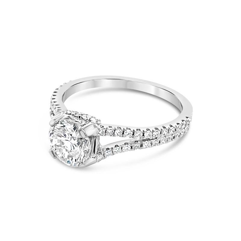 A 1.04ct round brilliant cut diamond, H I1, defines this engagement ring and features a split shank style band with 0.40ct total weight in round diamonds set in 18 karat white gold. This ring is currently a size 5.25 but can be resized upon request.