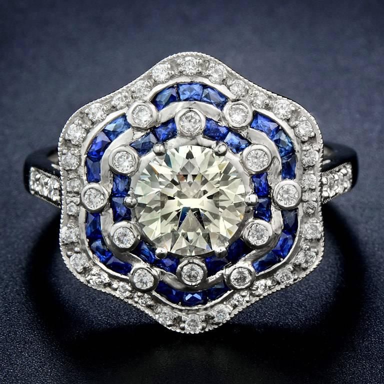 GIA Certified 1.05 Carat Weight Diamond K Color VS1 Clarity set in the center with Blue Sapphire French cut 18 pieces 1.70 Carat. Surrounded by Diamond 48 pieces total weight 0.34 Carat.

This Ring was made in Platinum 950 Size US#7

*The photos