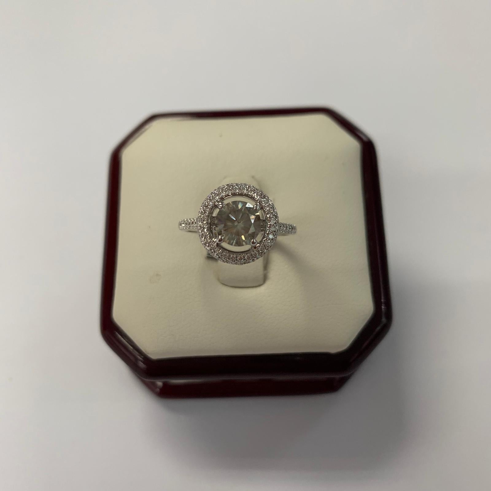 Fancy greenish yellow-gray natural round diamond weighing 1.05 carats by GIA.  Half way paved white diamonds in the halo setting. Its transparency and luster are excellent. set on 18K white gold, this ring is the ultimate gift for anniversaries,