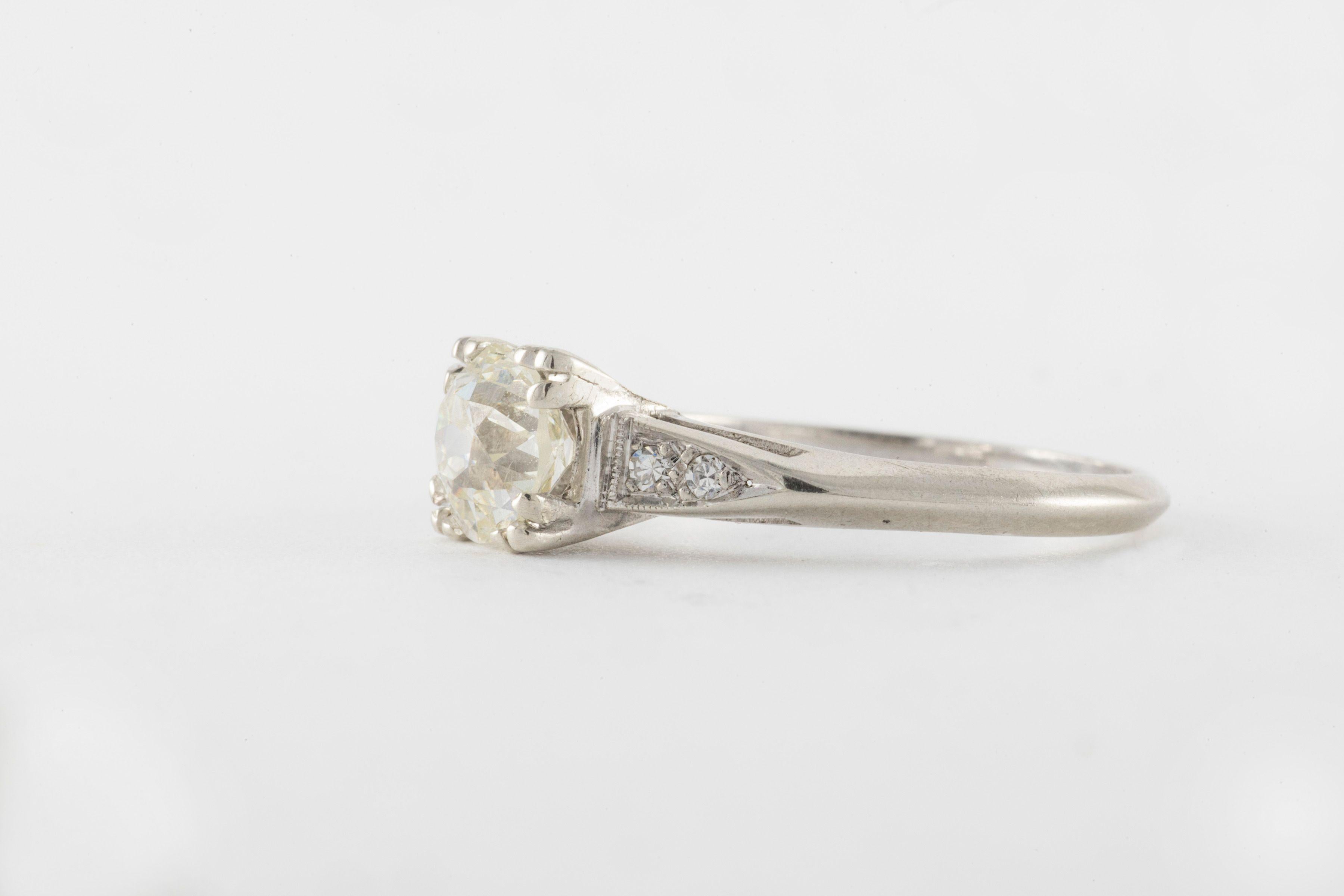 Un diamant de taille Vieille Europe pesant 1,08 carats, couleur N, pureté VS1 brille au centre de cette bague Art déco flanquée de quatre diamants taille unique totalisant environ 0,04 carats et sertie en or blanc 14 carats.
