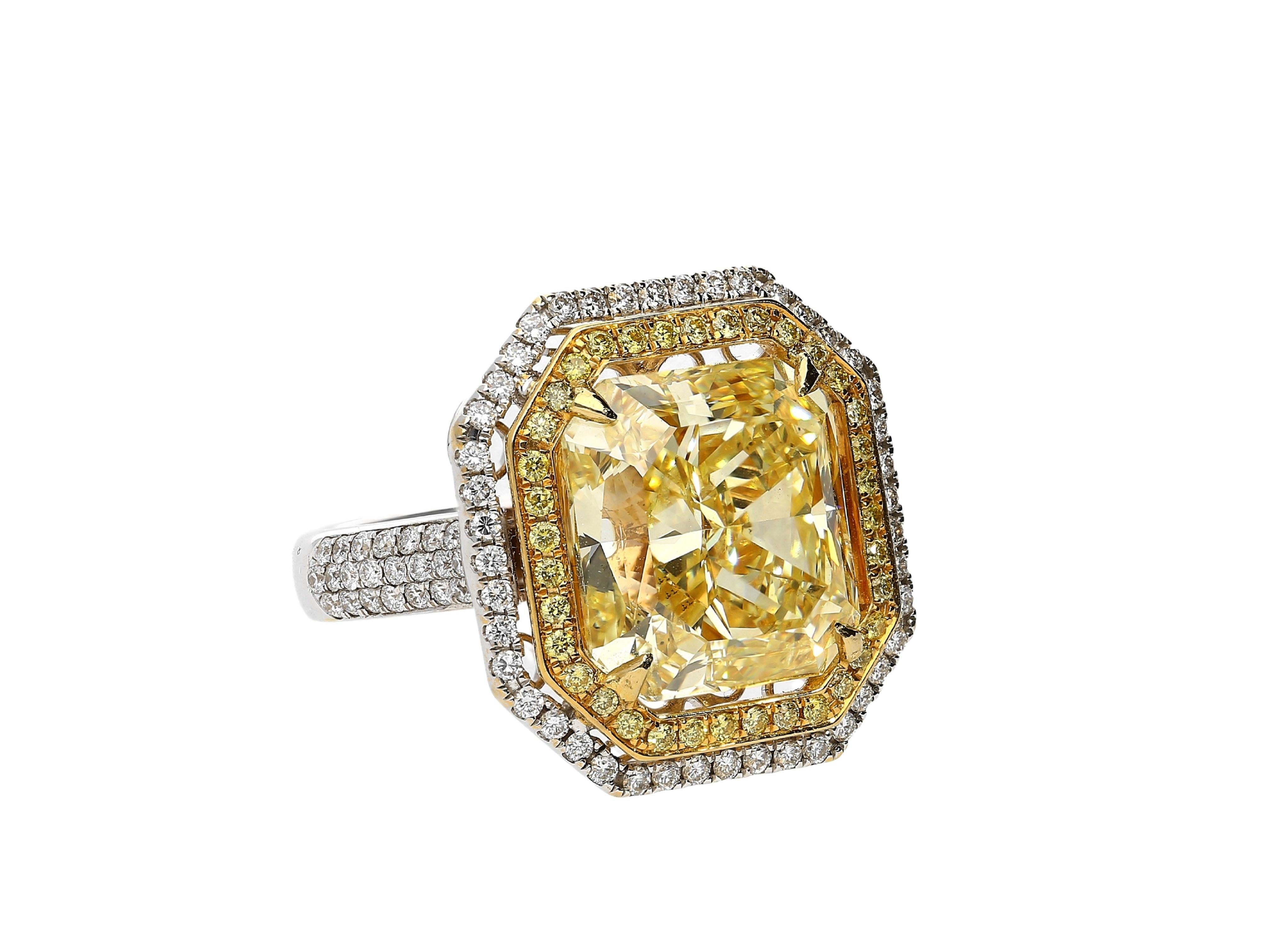 10.88 carat fancy yellow radiant cut diamond set with a 1 carat in white and yellow diamond halo. The ring setting is made in 18 karat white and yellow gold with an open back basket. This is done to ensure the culet is not covered and the stone's